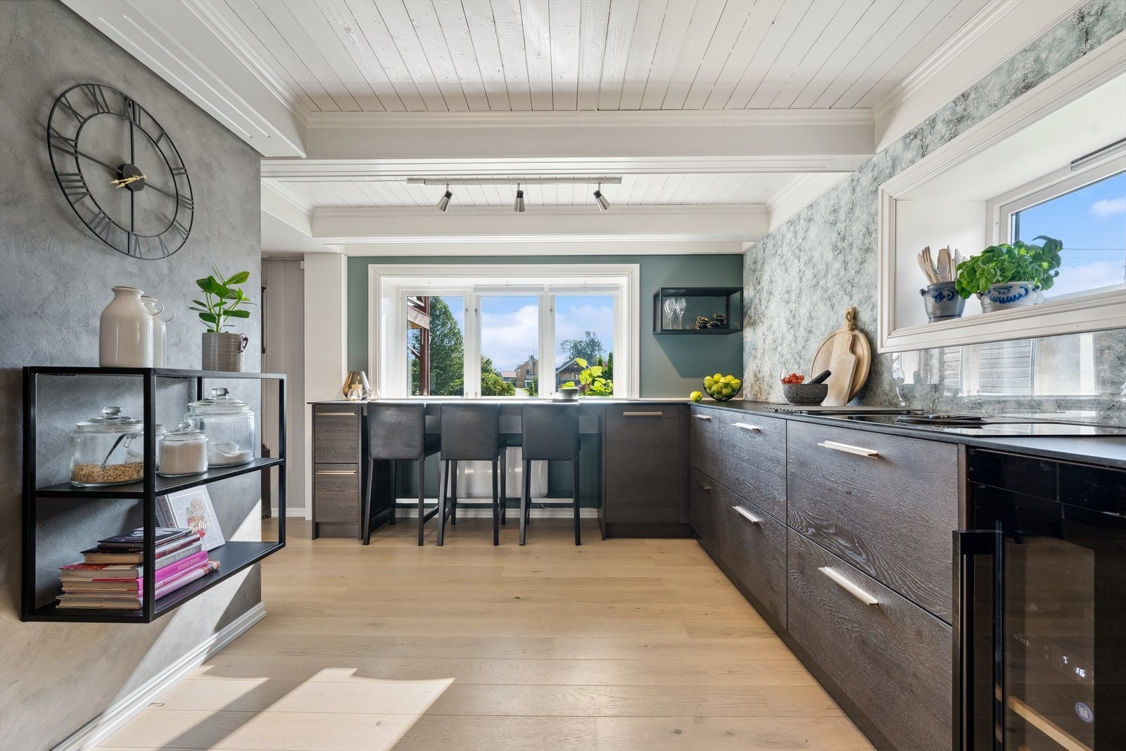 Innredningen har slette mørke eikefronter, kompaktlaminat benkeplate med nedfelt benkebeslag og ett-greps blandebatteri med waterquooker plassert i benkeskap. Galleribilde