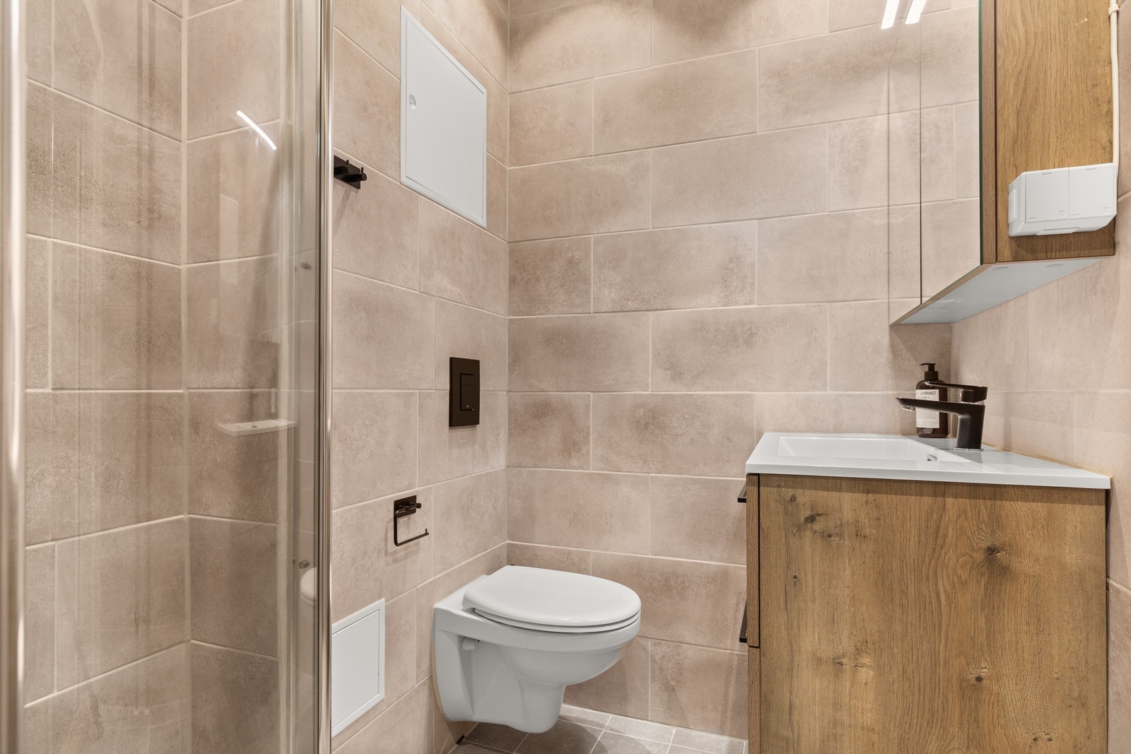 Badet ble rehabilitert i 2022 og er pent flislagt på gulv og vegger med varme i gulvet. Badet har dusjhjørne med dører og vegghengt toalett. Galleribilde