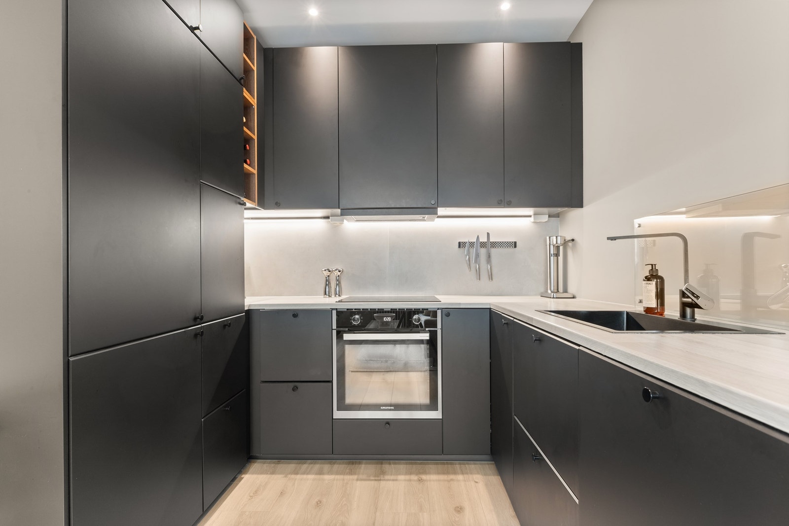 Delikat og lekkert kjøkken fra IKEA (2022). Kjøkkeninnredningen er av mørke, glatte fronter og benkeplate i laminat med nedfelt oppvaskkum Galleribilde