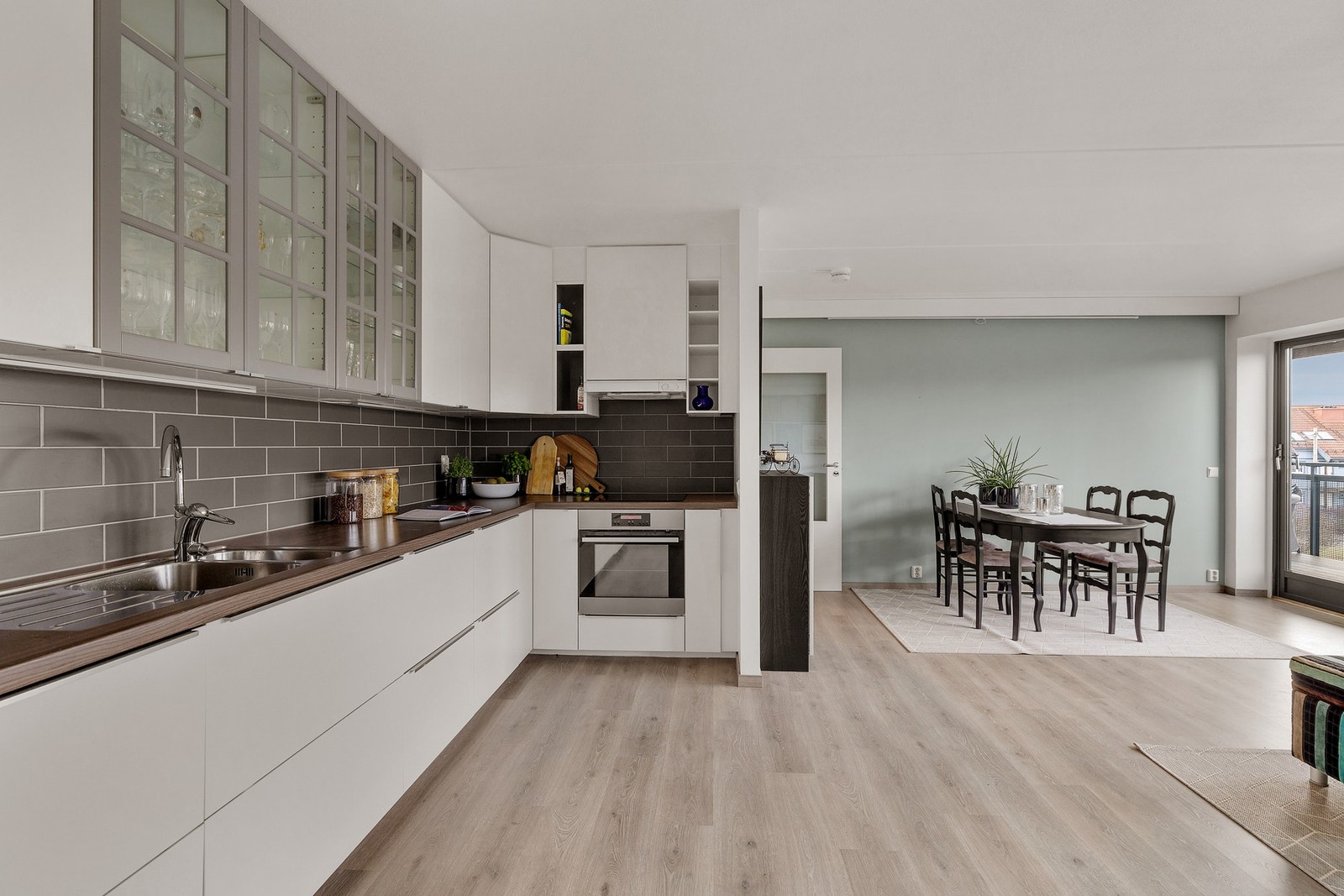 Kjøkkenet fremstår moderne med lyse overflater og integrerte hvitevarer Galleribilde