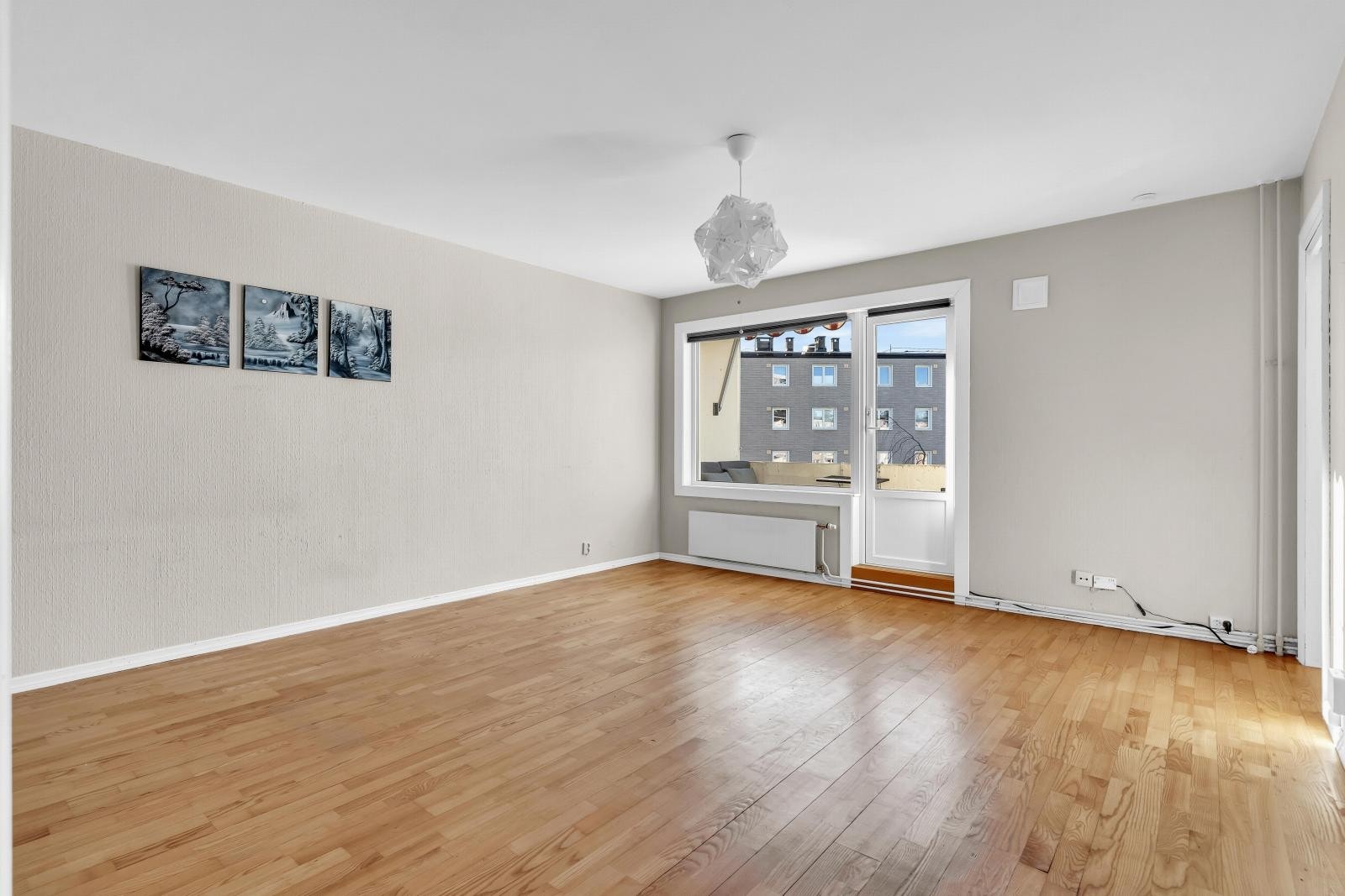 Lyst rom med store vinduer, parkettgulv og nøytrale vegger. Utgang til balkong med utsikt. Galleribilde