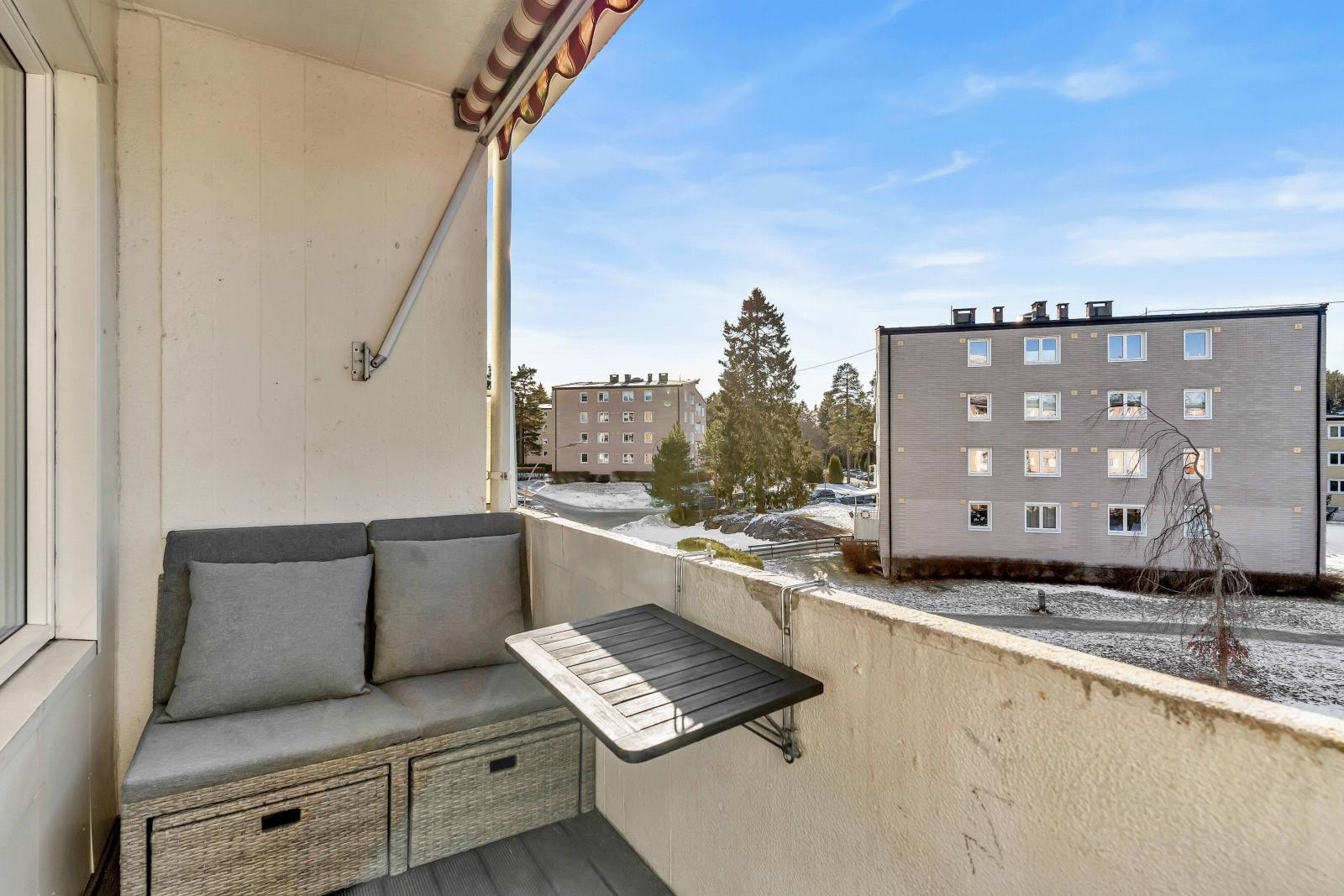 Balkongen har utsikt mot et rolig nabolag med blokker og trær. Den er utstyrt med en markise og har plass til sittemøbler. Galleribilde