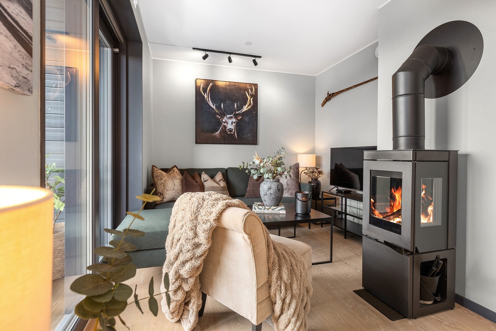 Koselig stueavdeling med en moderne peisovn og lyst tregulv. Veggene er malt i en nøytral farge og rommet gir en koselig atmosfære med stilren innredning. Galleribilde