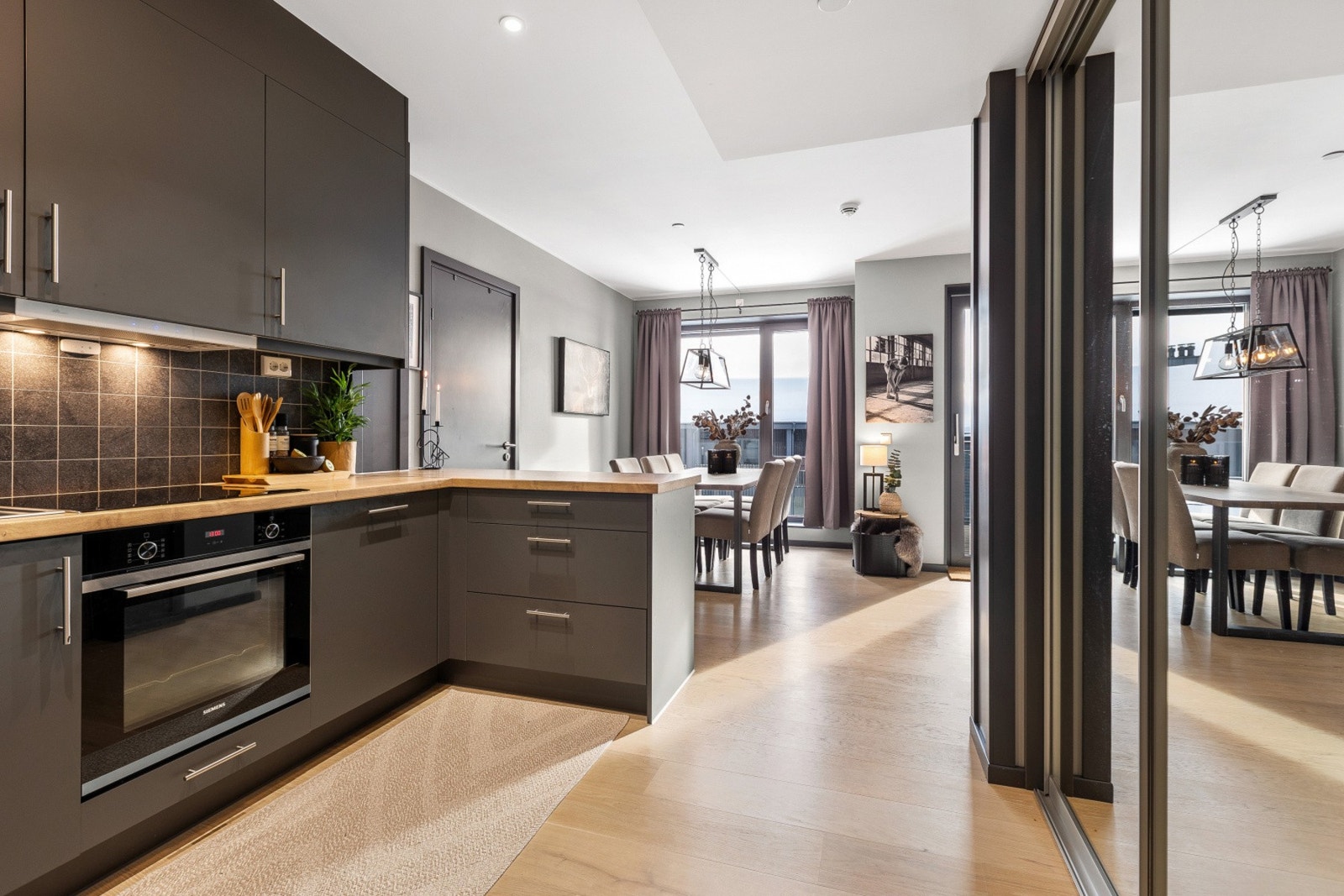 Moderne kjøkken med integrerte hvitevarer og åpen løsning mot spisestue. Grå slette fronter på kjøkkeninnredning gir et stilrent uttrykk. Galleribilde