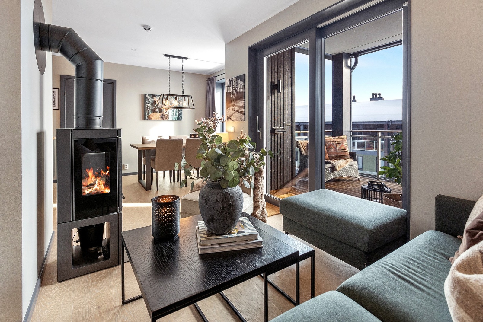 Lys og moderne stue med peis, store vinduer og utgang til balkong. Åpen løsning mot spisestue. Galleribilde