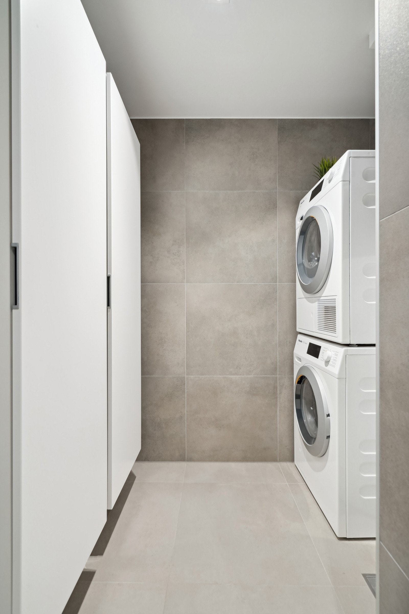 Praktisk nisje i bakkant av badet med to høyskap, varmtvannstank, vaskemaskin Galleribilde