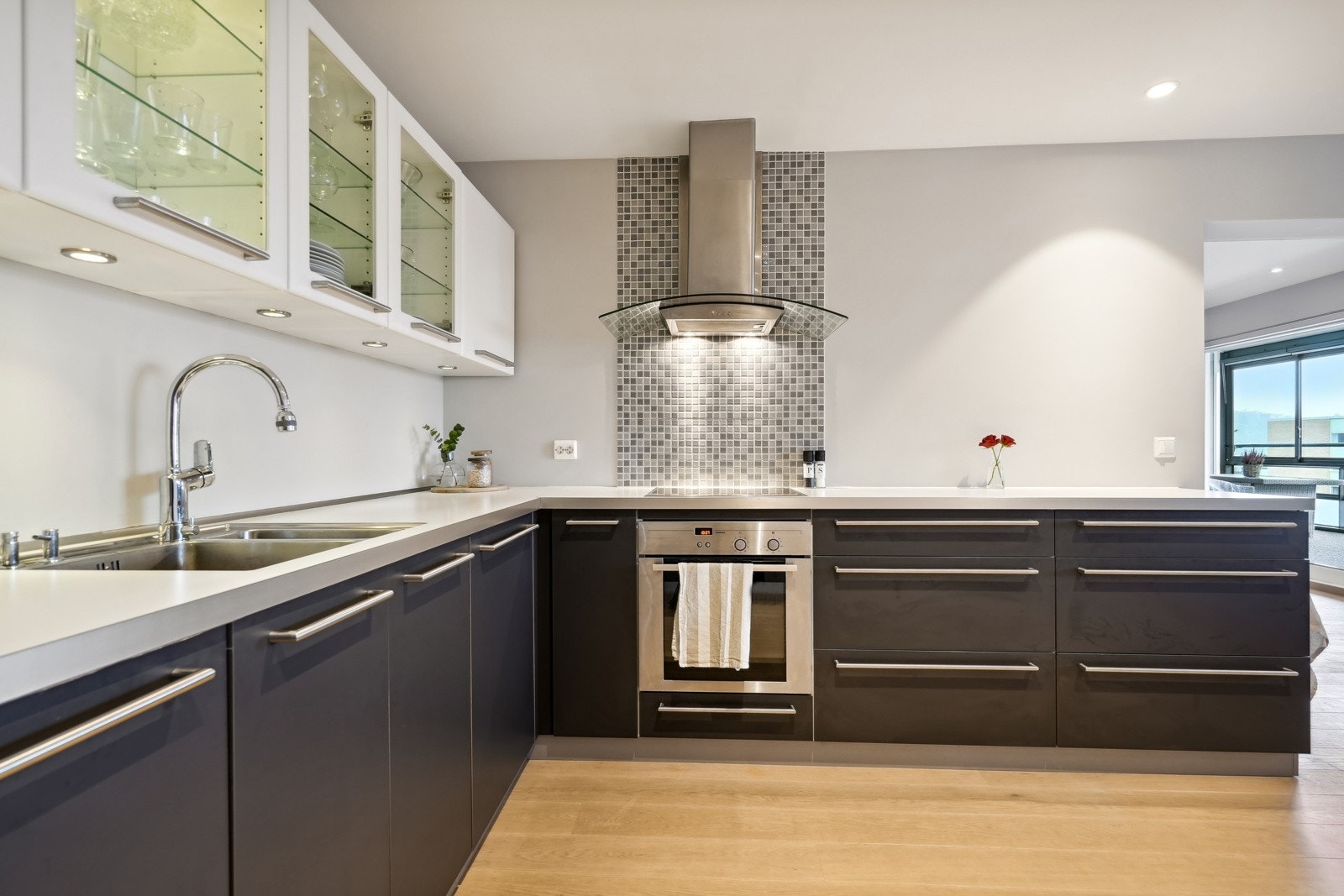 Det er belysning under overskap, og fliser på veggen bak koketopp. Takhengt avtrekksvifte av rustfritt stål over koketoppen. Galleribilde