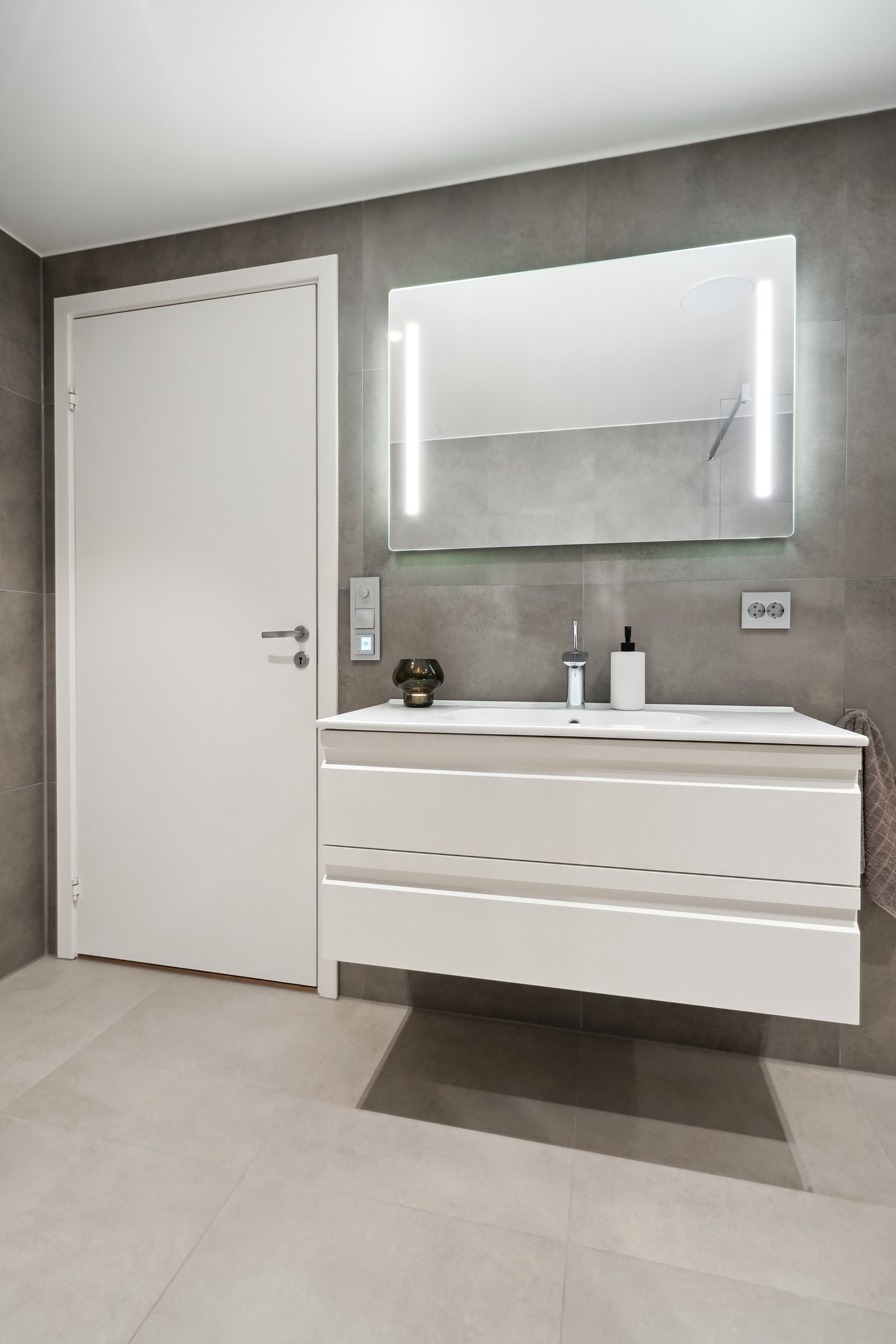 Fin innredning med skuffefronter og helstøpt servant og speil med belysning over. Galleribilde