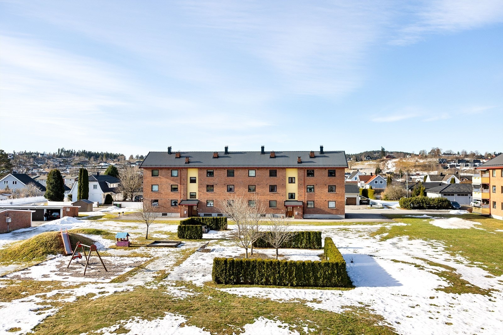 Grønne gressplener brer seg mellom byggene, omkranset av frodig beplantning og vakre prydbusker. Lekeområdene er strategisk plassert, slik at de små kan leke trygt og fritt i idylliske omgivelser. Galleribilde