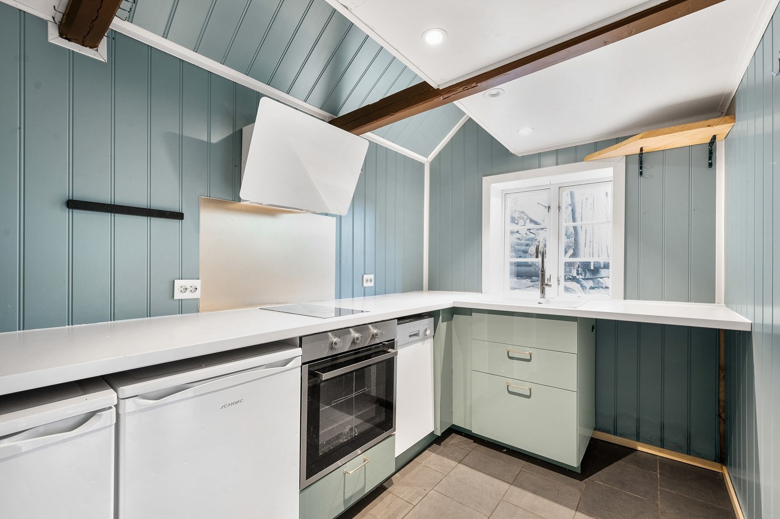 Kjøkken med hvite benkeplater, platetopp, avtrekksvifte og komfyr. Galleribilde