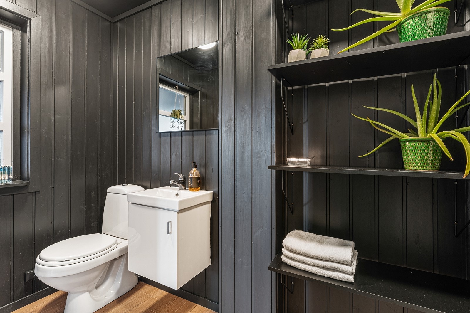 Badet har gulvfliser i dusjsonen og ellers laminat på øvrige deler av gulvet. Det er fliser på vegger i dusjsonen og ellers består veggene av panel. Galleribilde