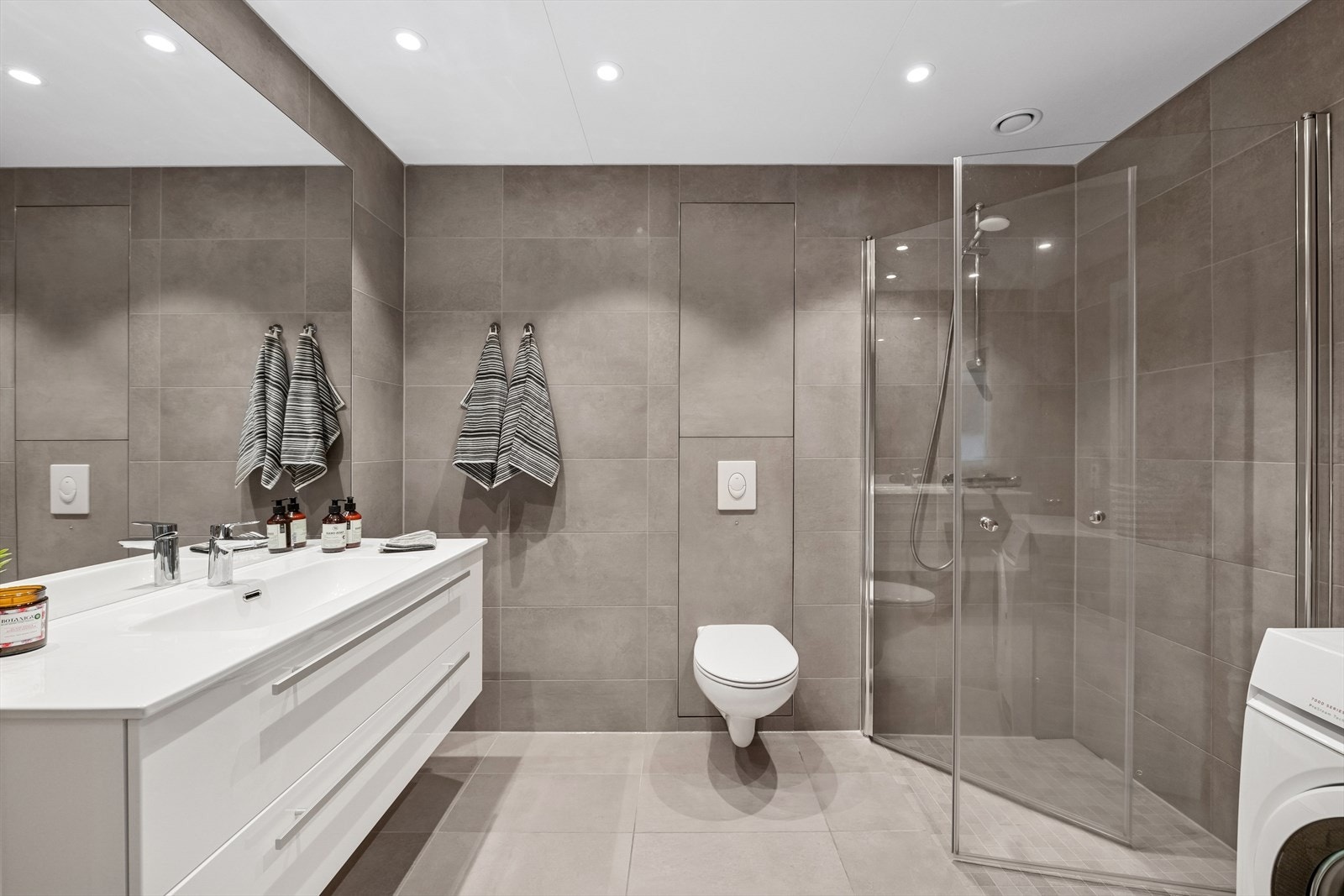 Bad med delikate, lyse fliser på gulv og vegger. Varmekabler i gulv. Galleribilde