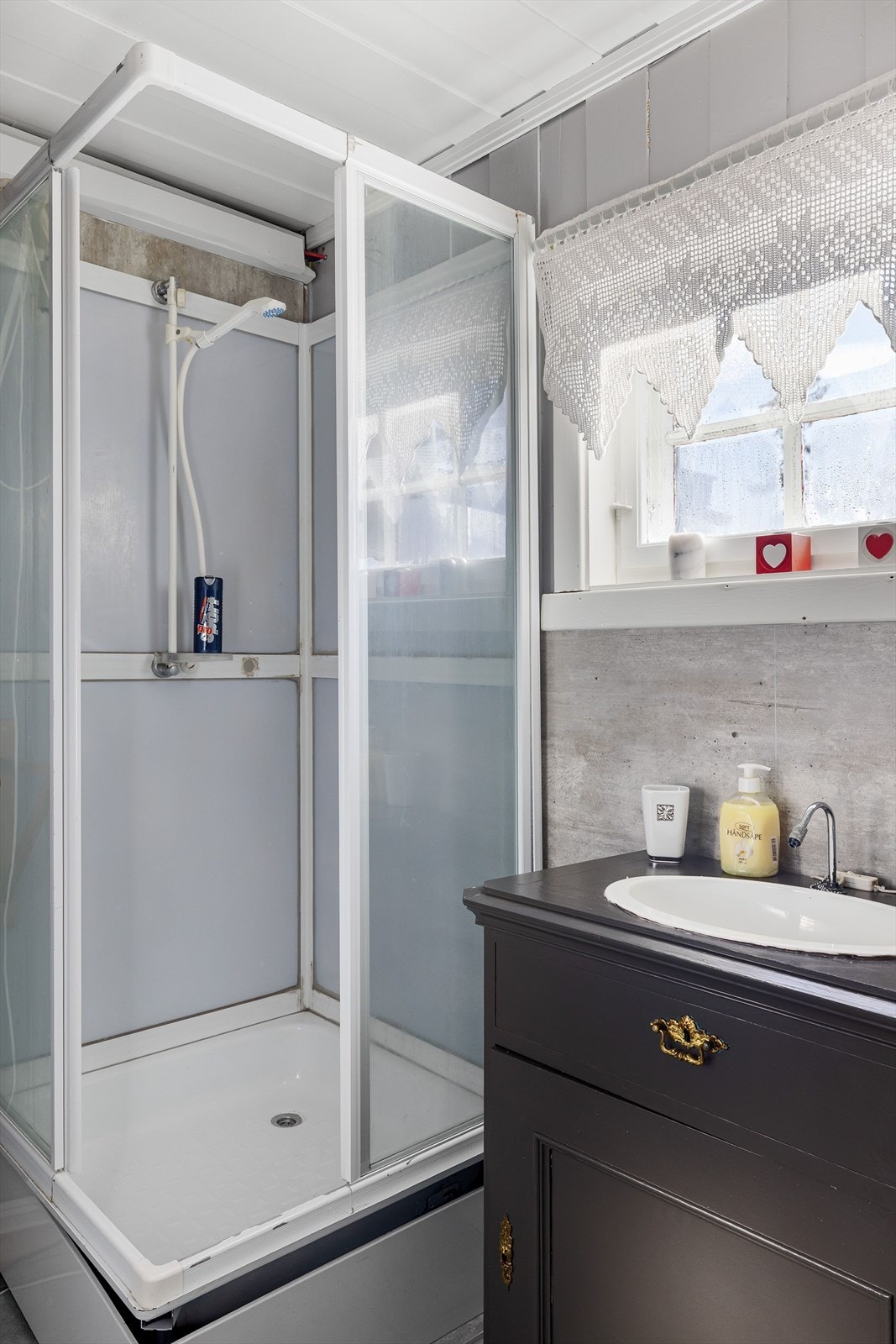 Malt kommode med nedsenket servant og dusjkabinett. Vannbeholder med elektrisk pumpe og strøm fra solcellepanel til dusj og servant. Avløp med rør ut til terreng. Galleribilde