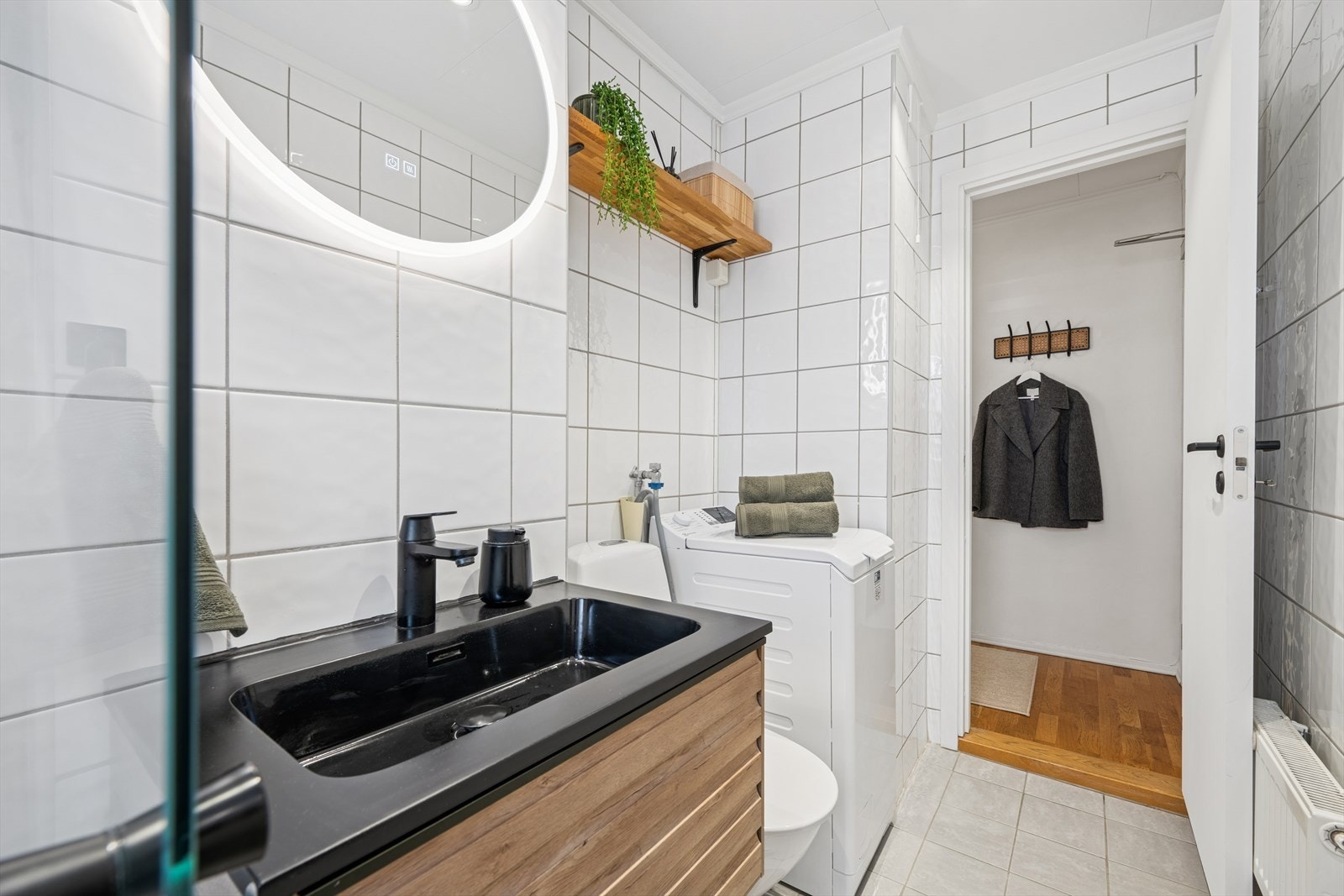 Badet er innredet med servant med profilerte fronter, gulvstående toalett, dusjhjørne med glassvegger samt to opplegg for vaskemaskin, noe som gir ekstra fleksibilitet. Galleribilde