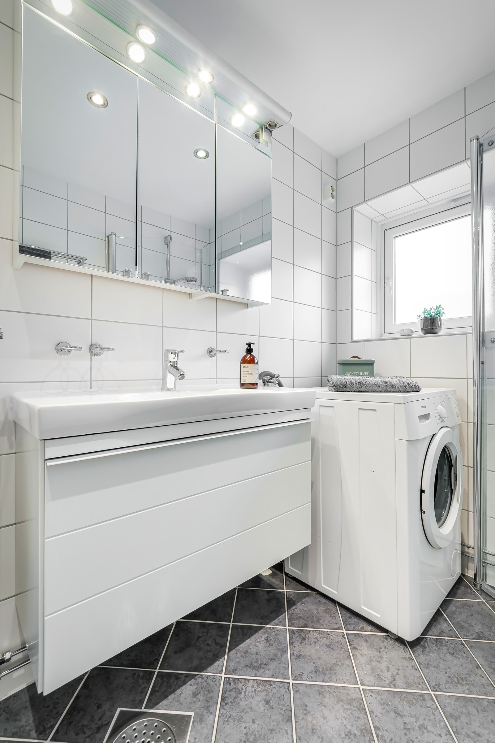 Baderommet har mørke fliser på gulv med gulvvarme, lyse fliser på veggene og downlights i himlingen. Også på baderommet er det et vindu som slipper inn deilig dagslys. Galleribilde