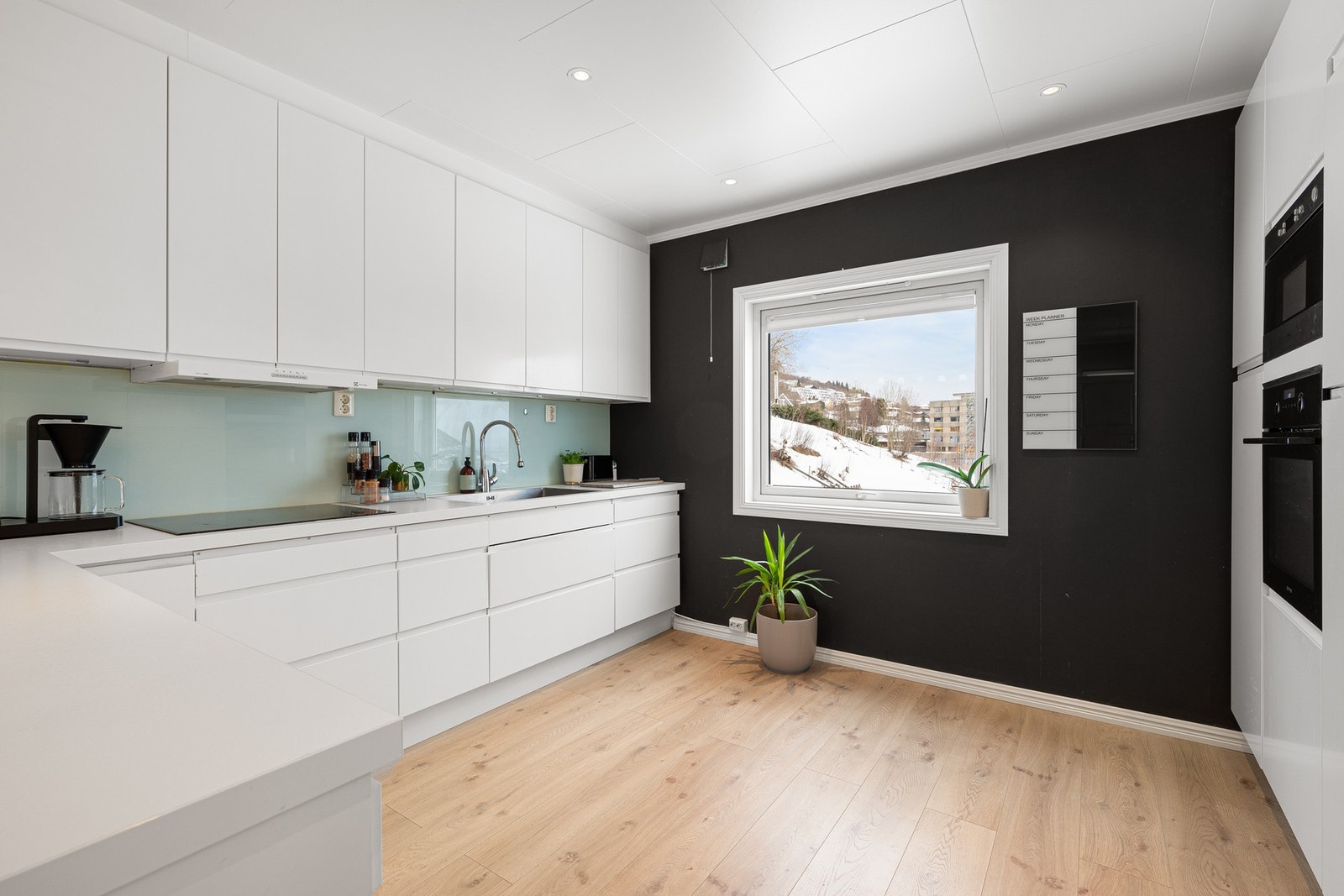 Stilren kjøkkeninnredning med glatte fronter og benkeplate av laminat - skuffer under benkeplate gir praktisk oppbevaring Galleribilde