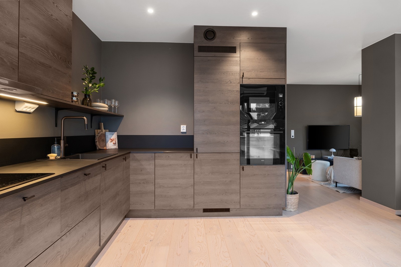 Kjøkkeninnredning fra Strai kjøkken. Gjennomtenkte og stilrene løsninger med sorte detaljer på bankeplate, håndtak og de integrerte hvitevarene. Galleribilde