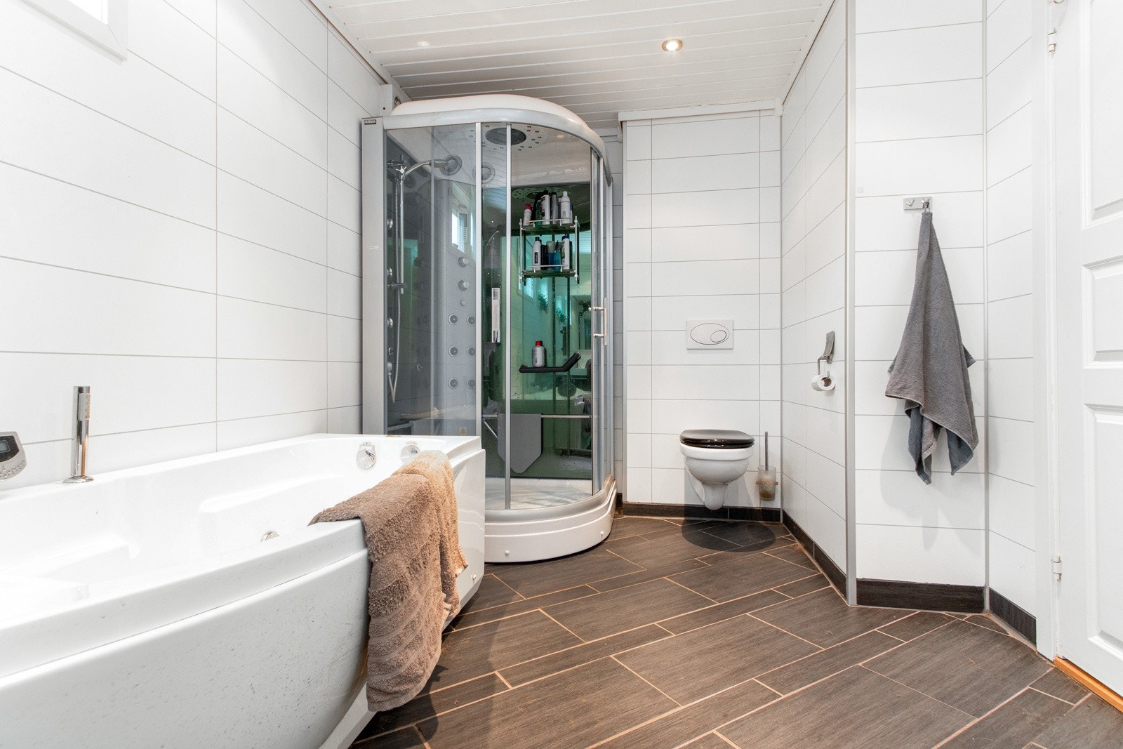 Videre har badet en stor skyvedørsgarderobe, et vegghengt toalett, et badekar og et multifunksjonelt dusjkabinett. Galleribilde
