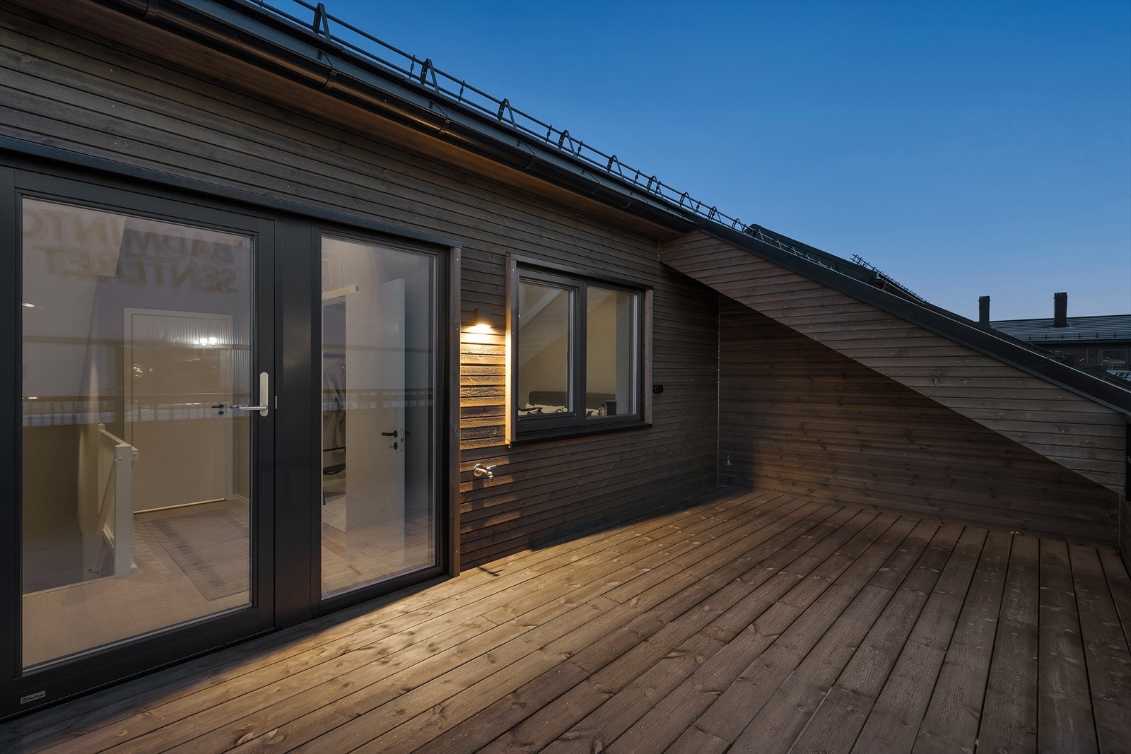 Moderne takterrasse i treverk med stilfull belysning. Perfekt for avslapning og sosiale sammenkomster. Galleribilde