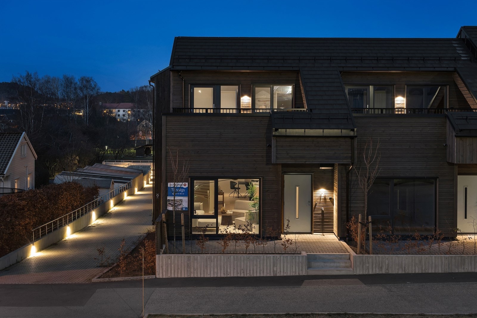 Moderne rekkehus med stilfull fasade, idyllisk beliggende nær naturen. Opplyst gangvei og innbydende atmosfære. Perfekt for familier. Galleribilde