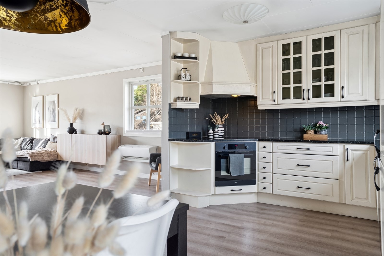 Over benken har kjøkkenet fliser og en hetteventilator med belysning. Galleribilde