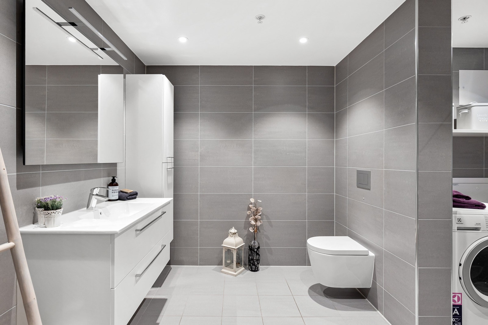 Boligens bad er pent flislagt på gulv og vegger med vannbåren varme i gulvet. Badet er innredet med vegghengt klosett, servant nedfelt i innredning og speil med belysning. Galleribilde