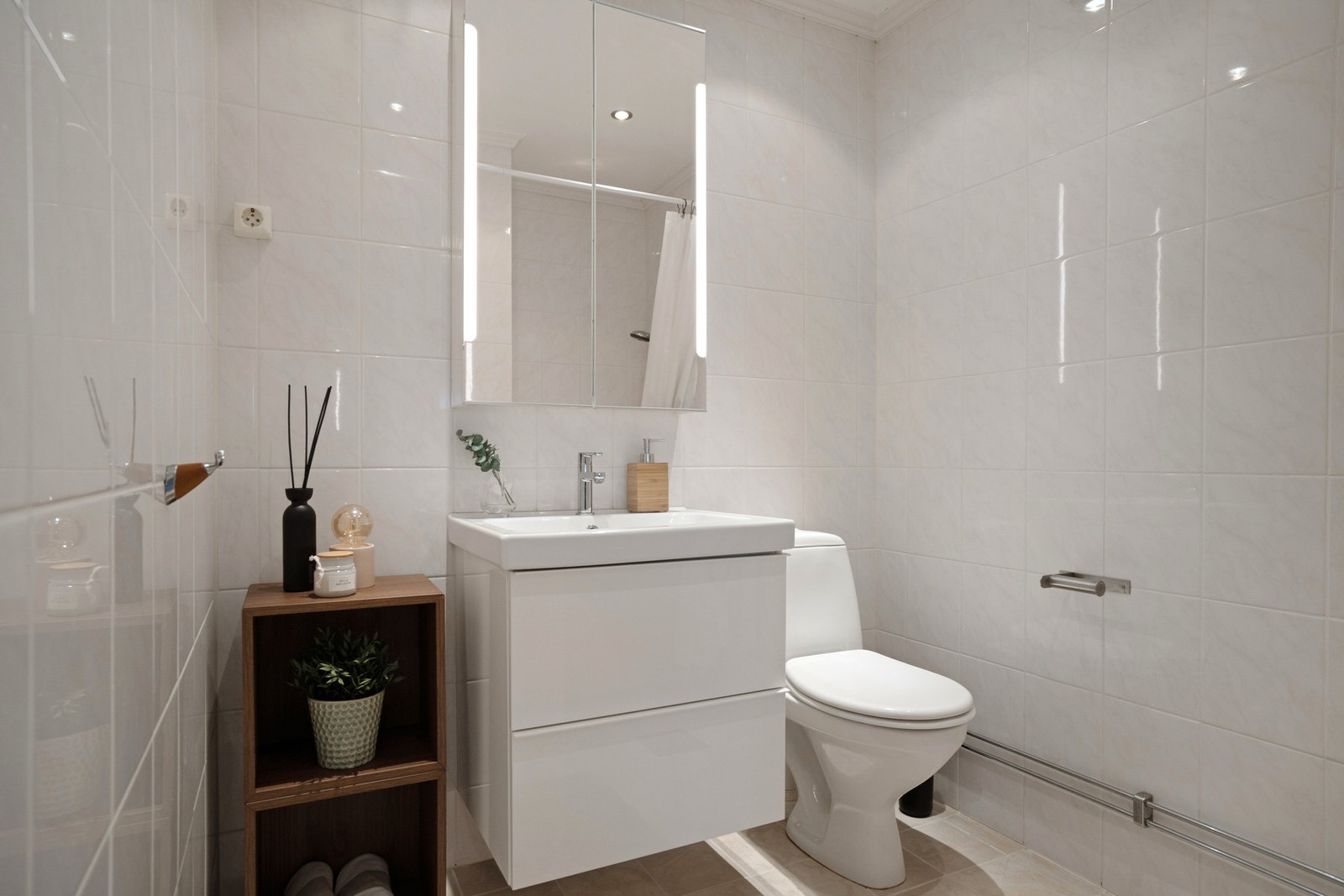 Flislagt bad med nedfelt vask, toalett og dusjhjørne. Det er varmekabler i gulv og opplegg for vaskemaskin. Galleribilde