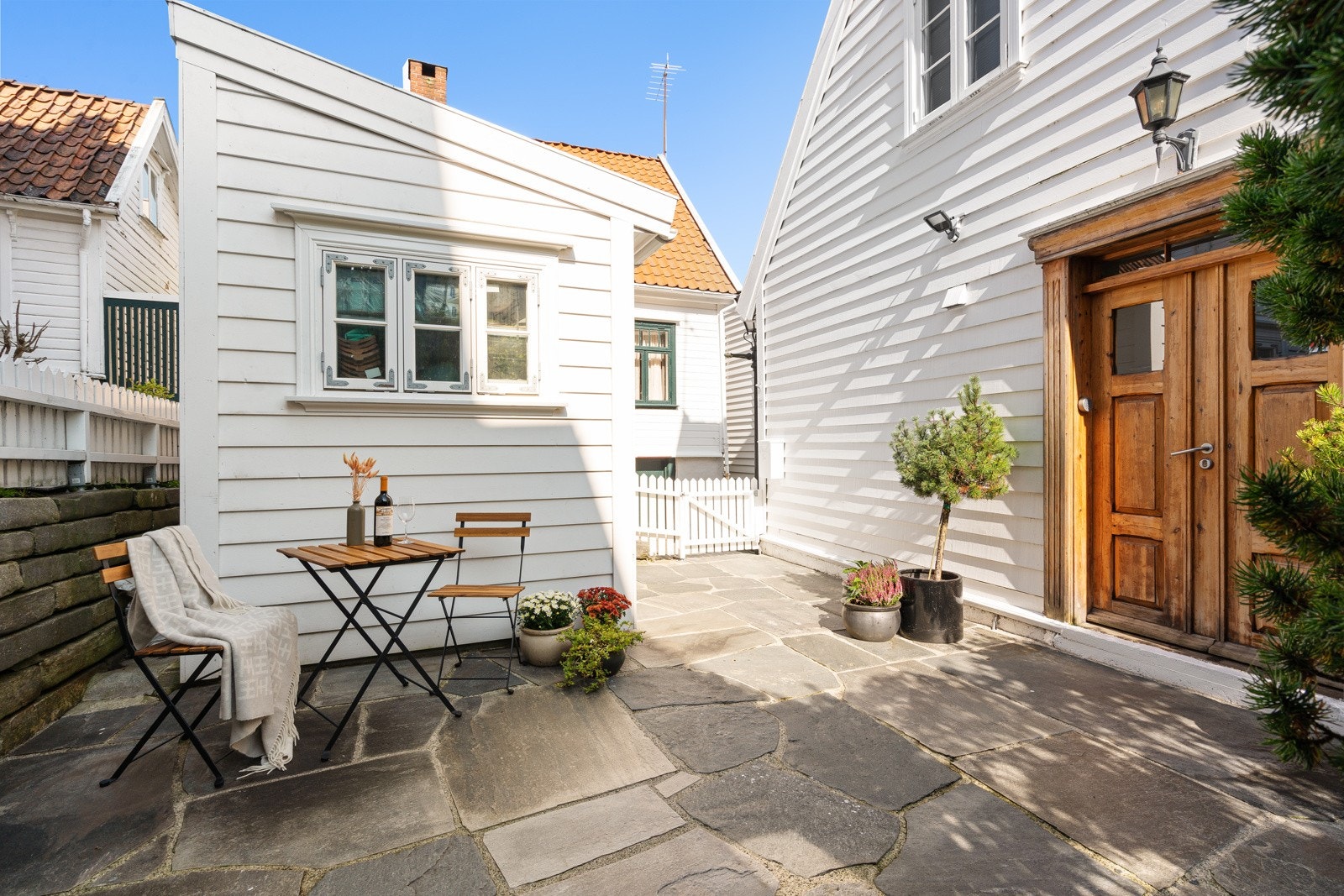 Bak et hvitt stakittgjerde i idylliske brosteinsbelagte gater finner man Clausegata 2. Galleribilde