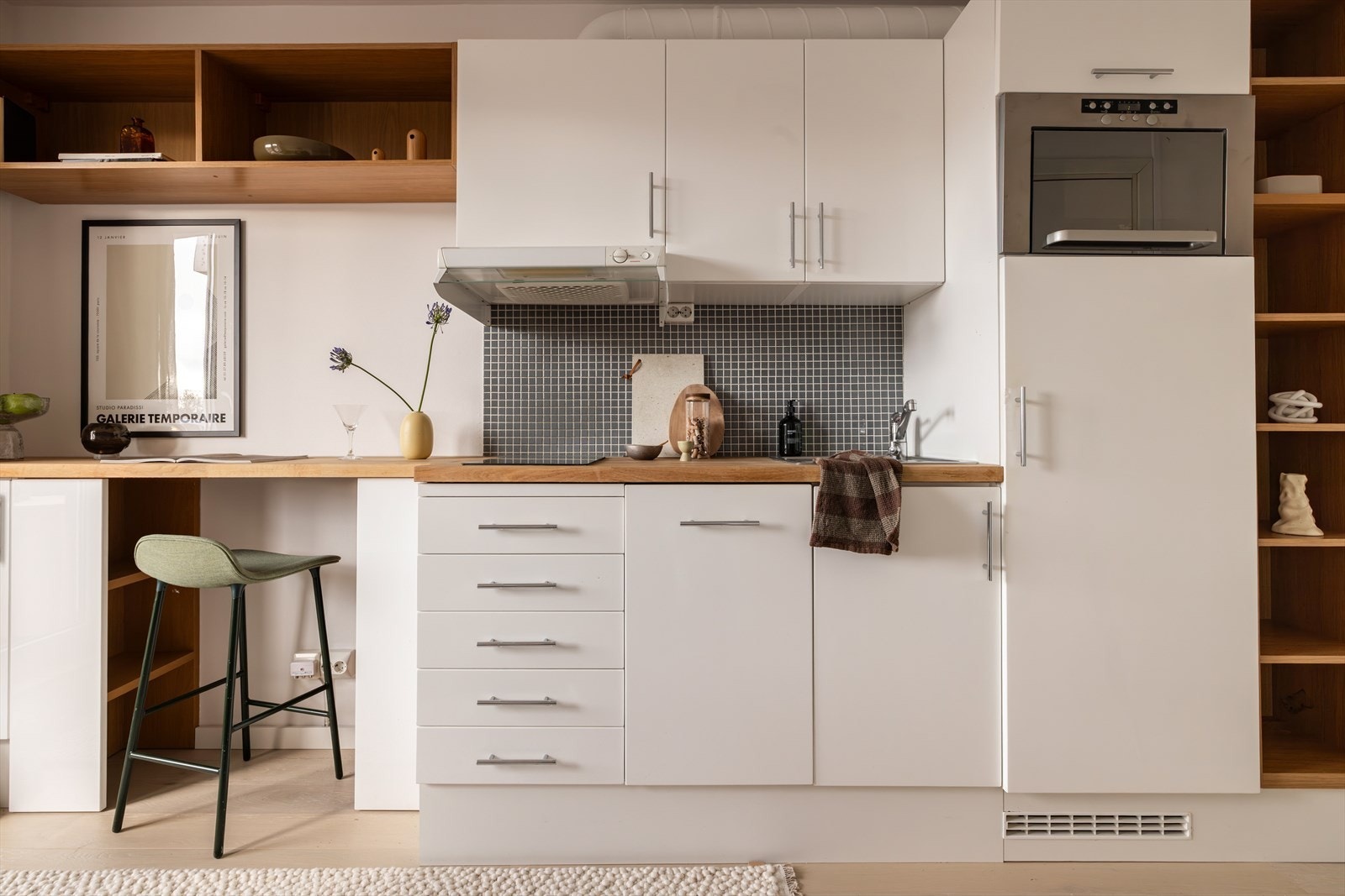 Leiligheten har et åpent kjøkken med hvite, tidløse fronter. Galleribilde