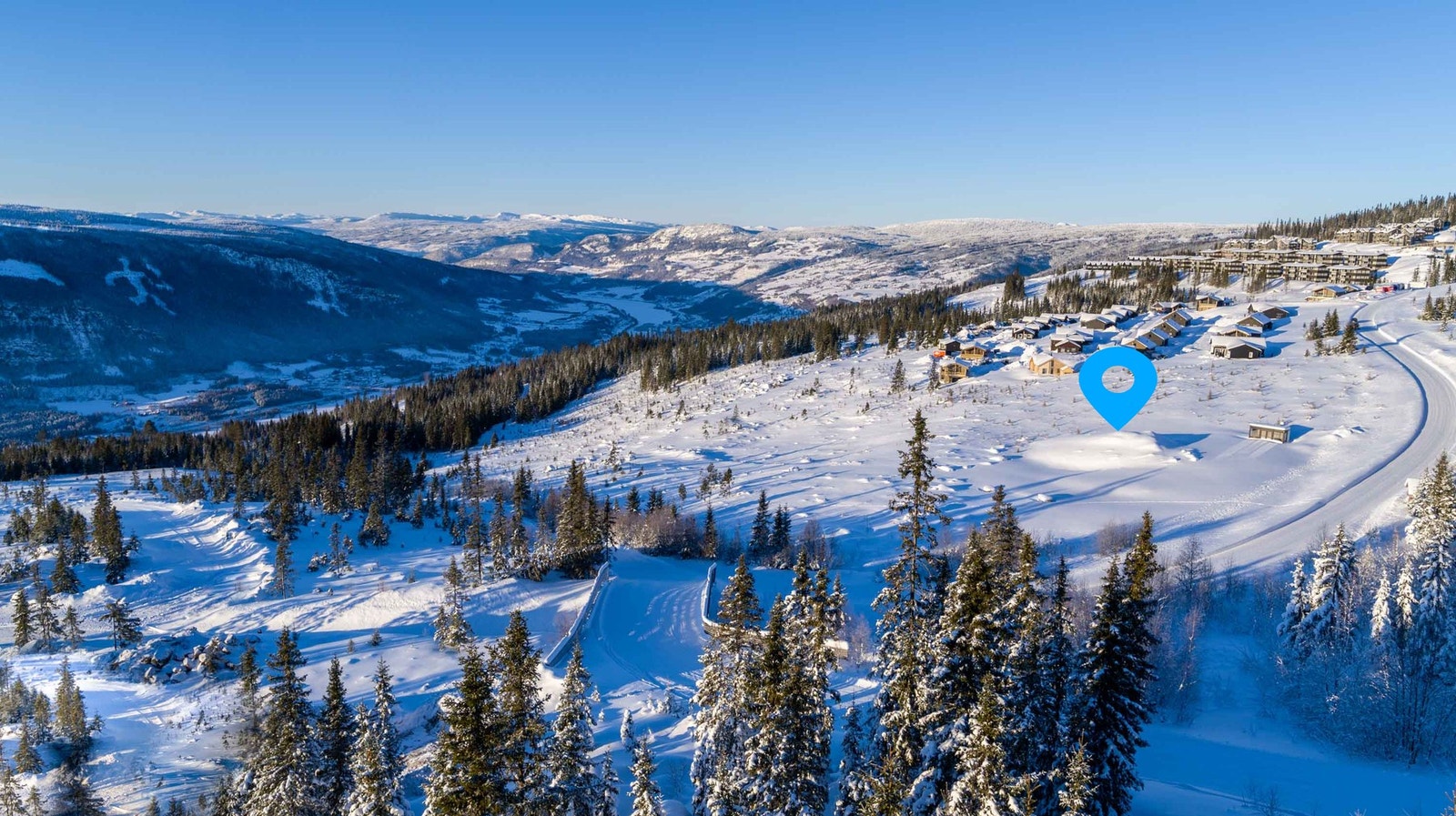 Dronefoto over tomteområdet. Skibru over veien sørger for sikker og god adkomst både til og fra tomteområdet på ski Galleribilde