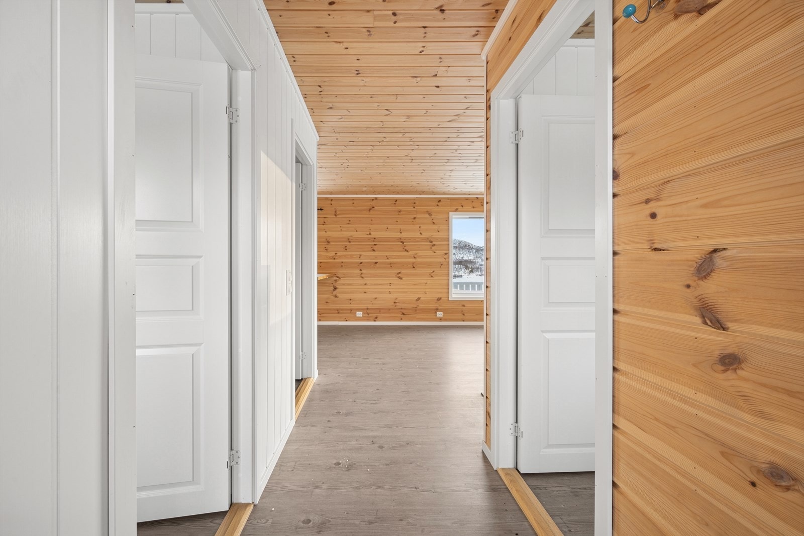 Hytta har en kombinasjon av hvitmalt panel, trehvitt panel og laminatgulv. Galleribilde