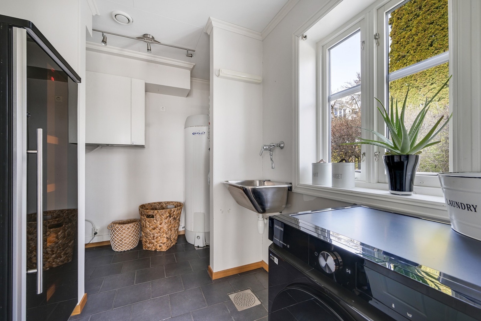 Flislagt gulv, skyllekum og plass for både vinskap, vaskemaskin og trommel Galleribilde