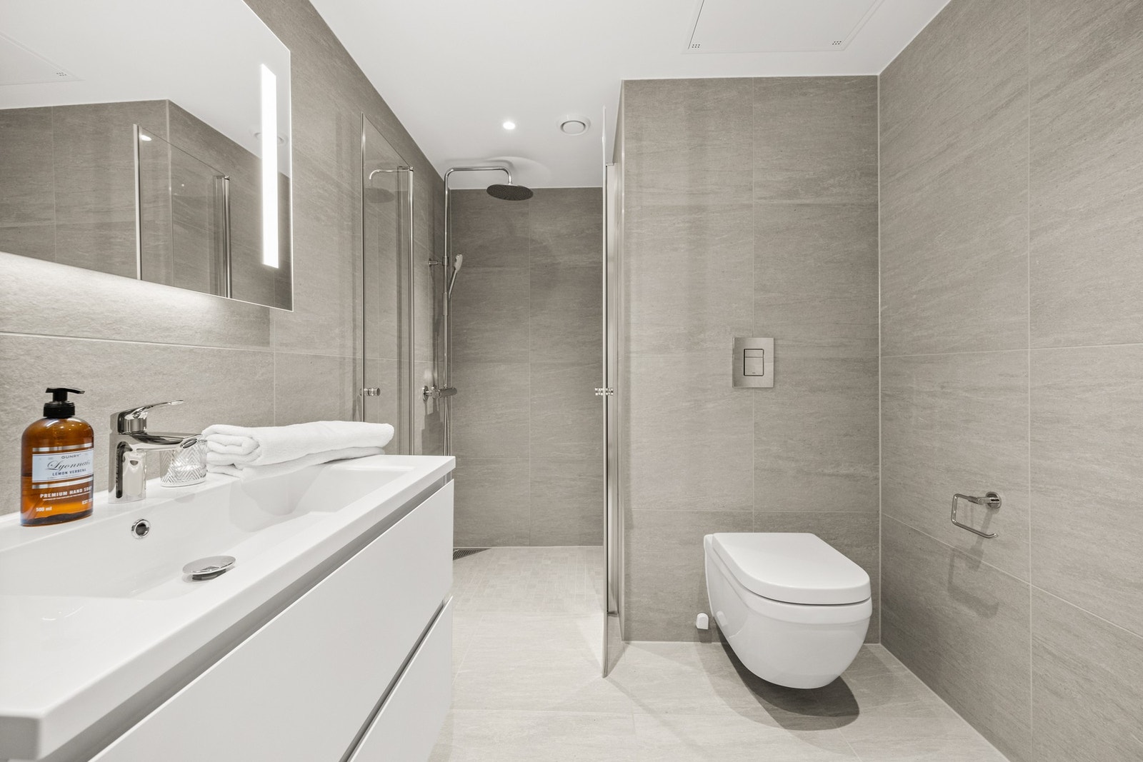 Det flislagte badet har downlights i tak, vannbåren gulvvarme og opplegg for vaskemaskin og tørketrommel Galleribilde