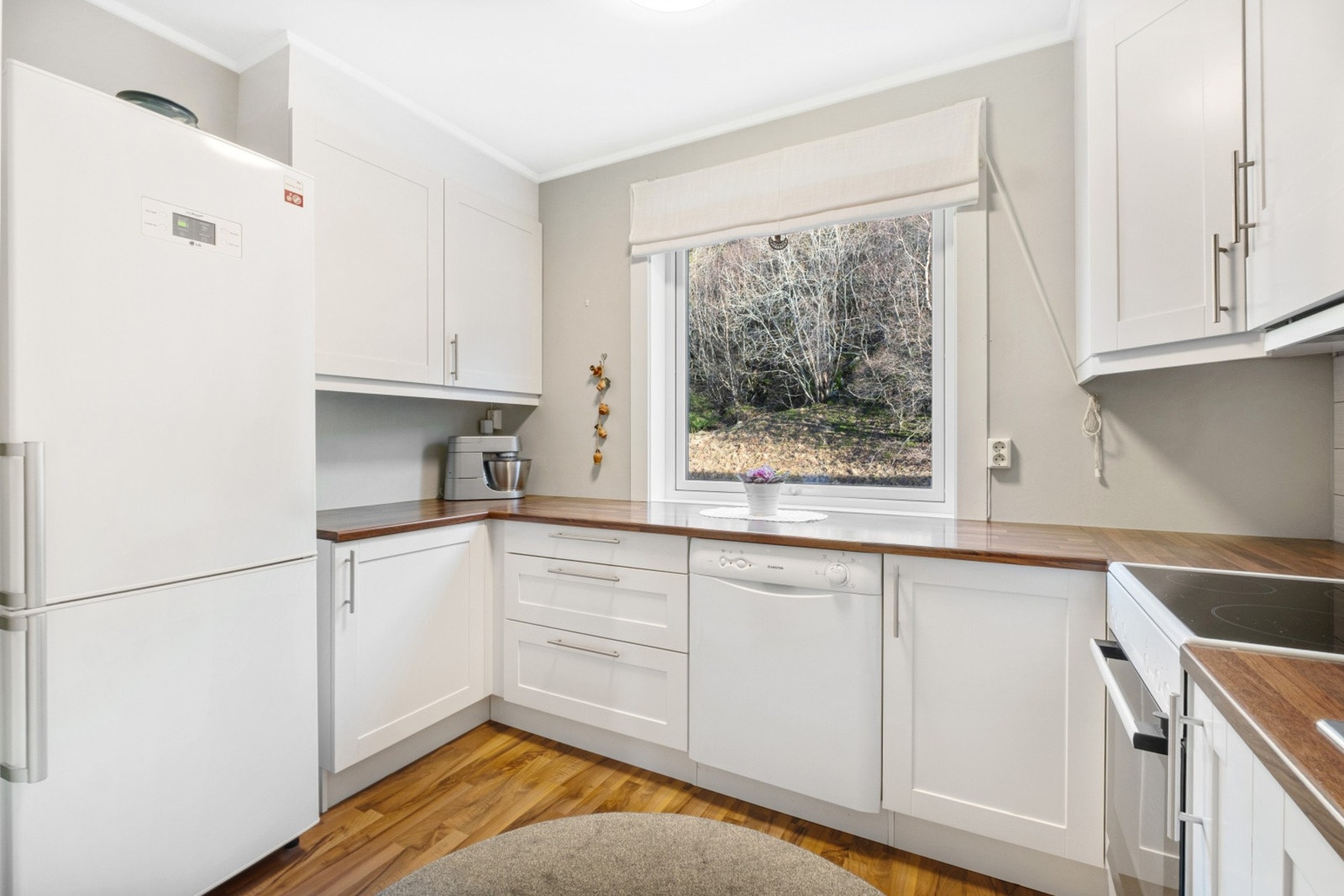 Innredet med hvite fronter, benkeplate i laminat og fliser over benk. Galleribilde