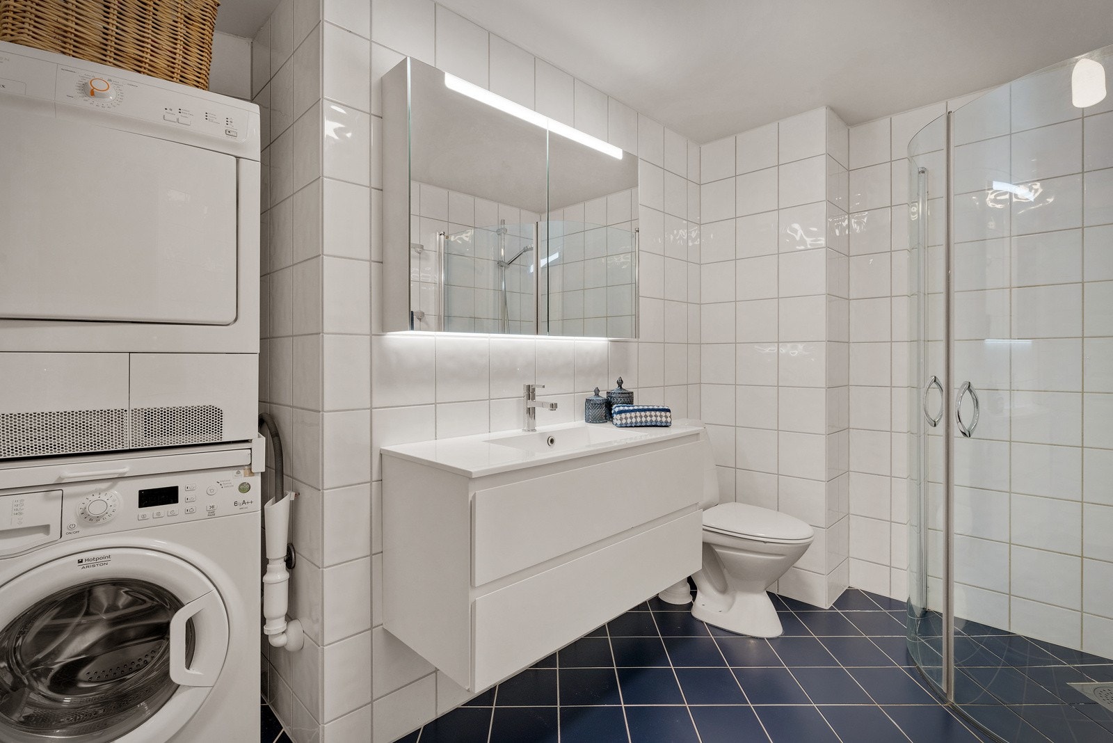 Romslig helfliset baderom med opplegg for vaskemaskin og tørketrommel. Galleribilde