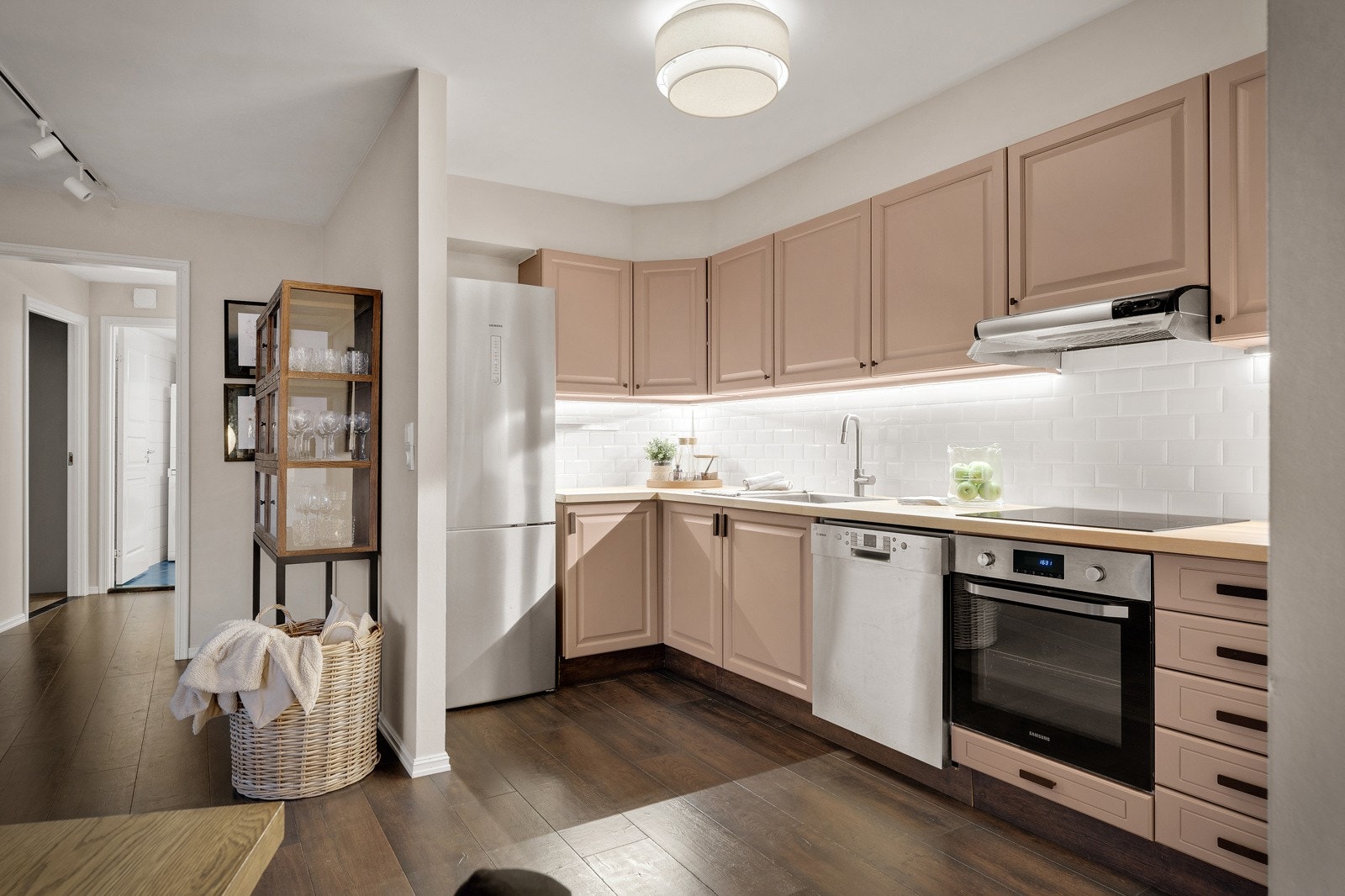 Pen kjøkkeninnredning med malte fyllingfronter og laminat benkeplate med topplag av finer og nedfelt stål vaskebeslag. Galleribilde