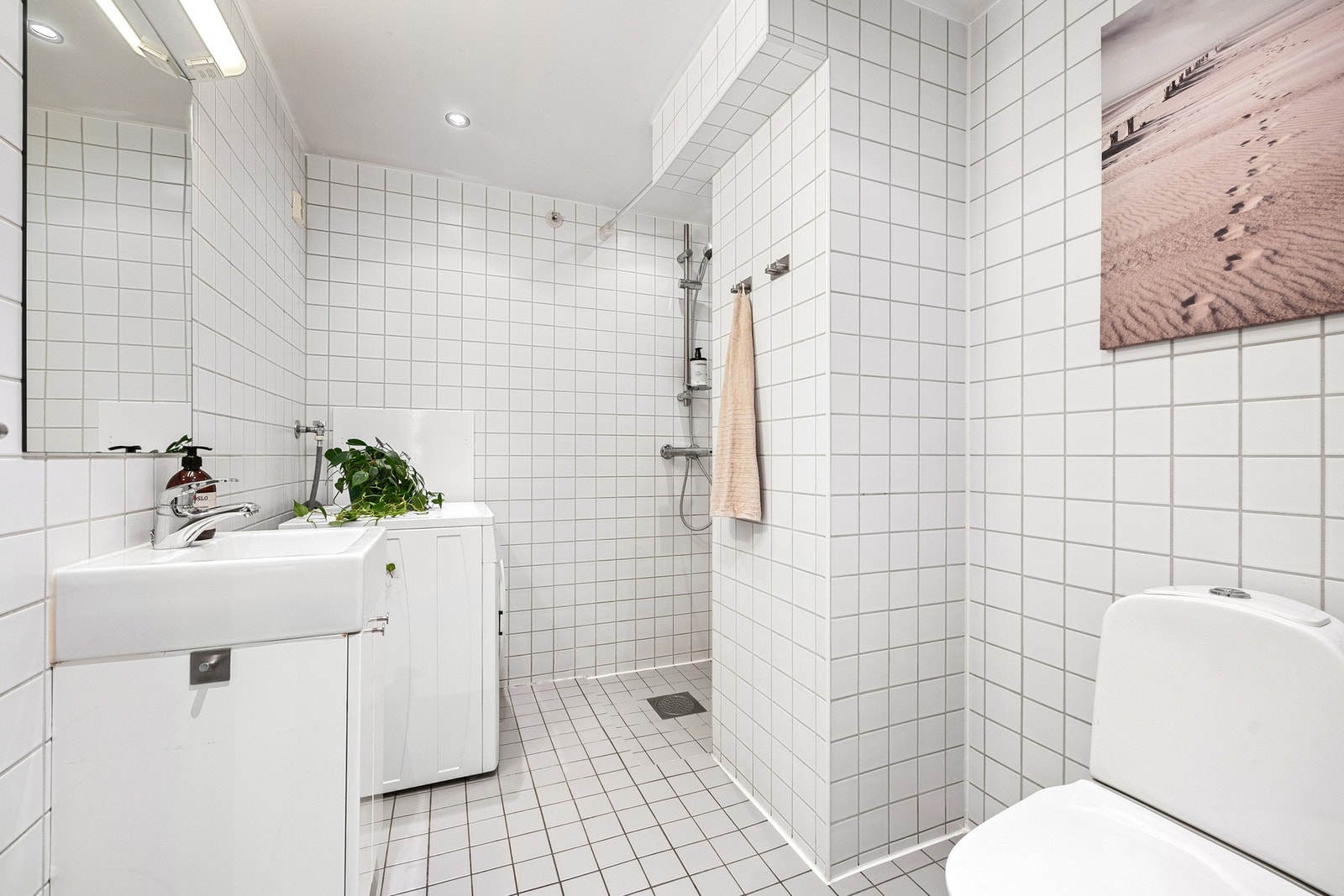 Flislagt bad av god størrelse med varmekabler i gulv og opplegg for vaskemaskin. Galleribilde