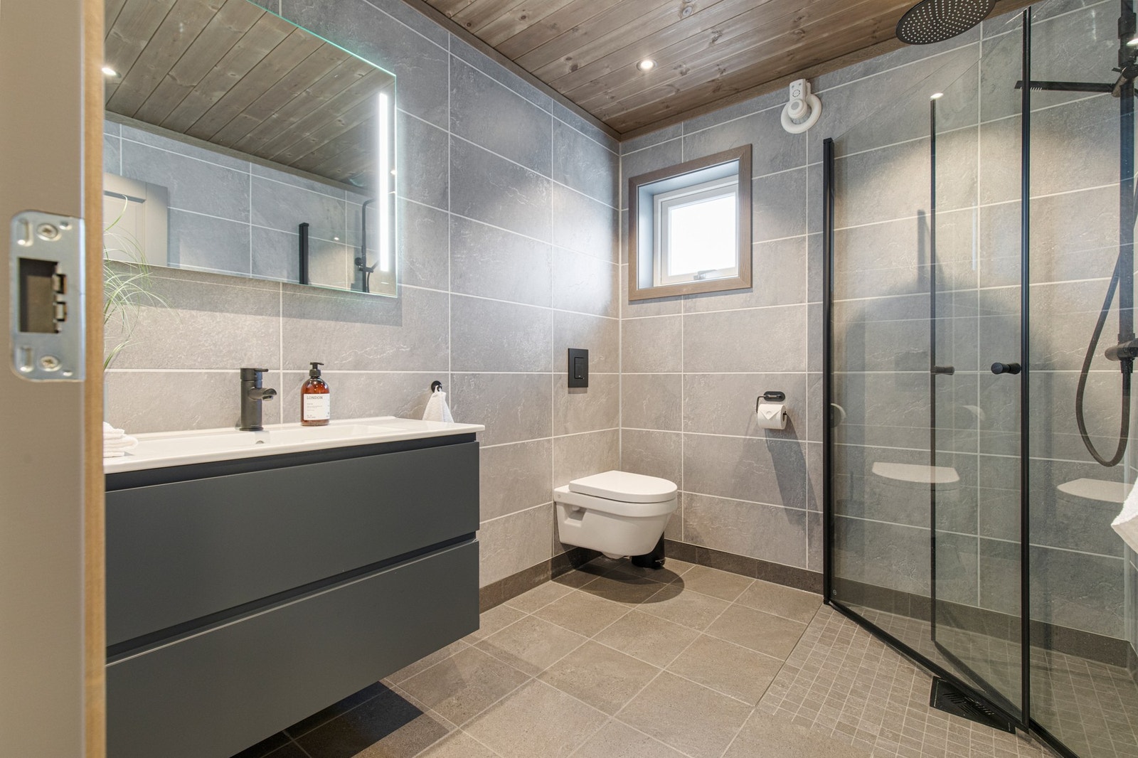 Innredning med glatte skuffefronter med grepskant, og speil med belysning over helstøpt servant. Galleribilde