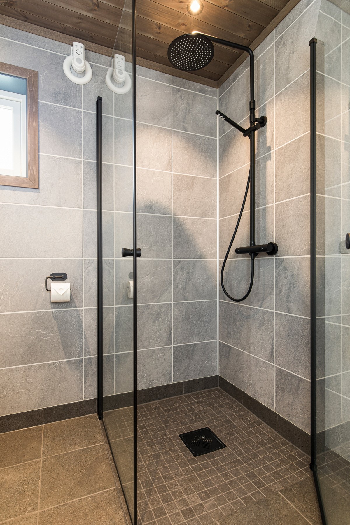 Utstyrt med vegghengt toalett, og dusj med innfellbare glassdører. Sort dusjarmatur på vegg. Galleribilde