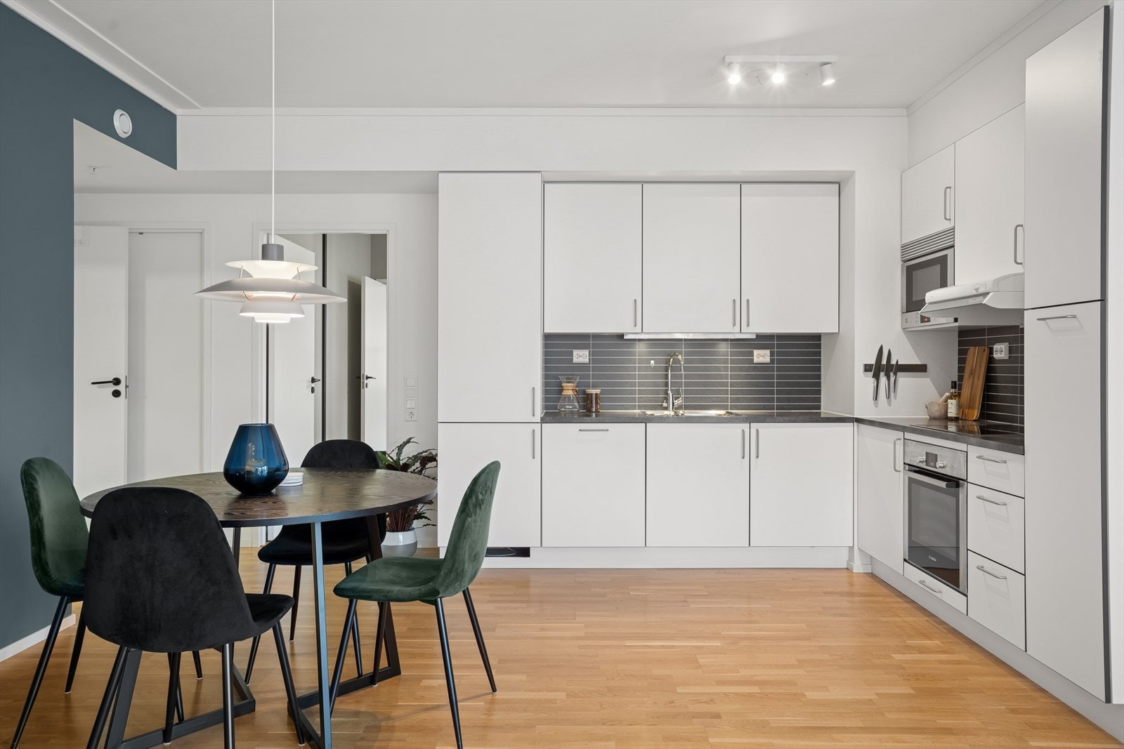 Kjøkken er tidløst med hvite slette fronter med stålhåndtak Galleribilde