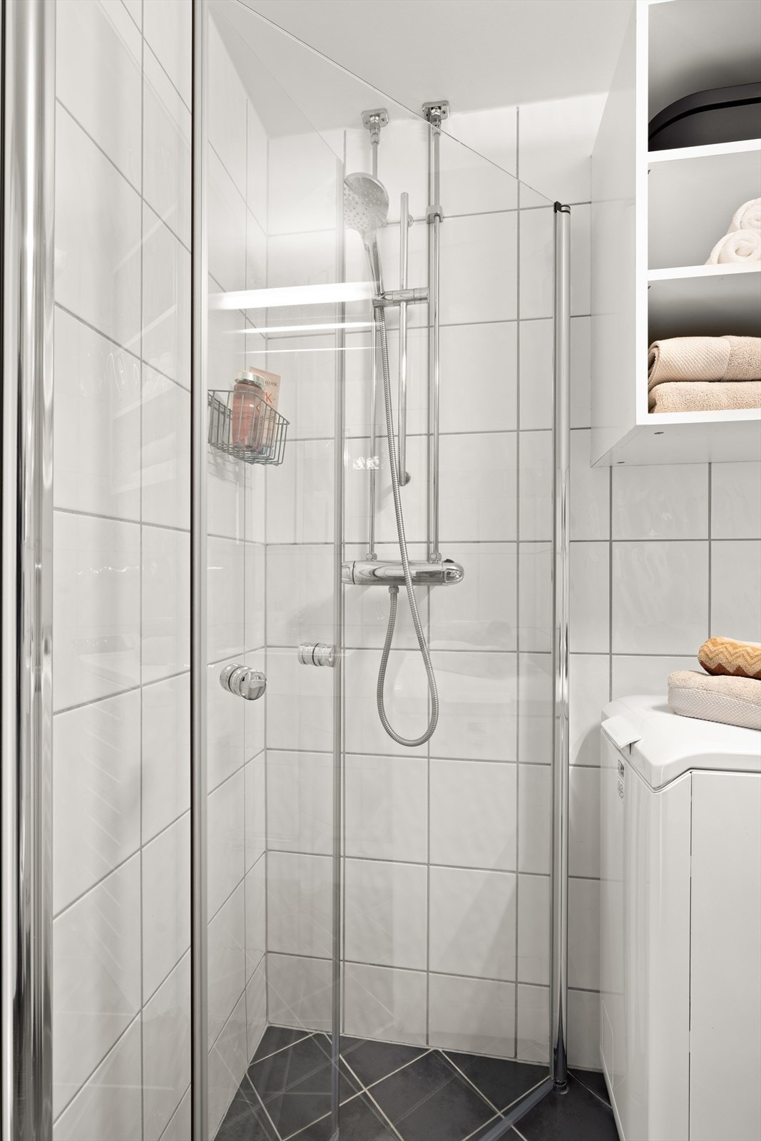 Badet har praktisk dusjhjørne med innfellbare dusjdører, opplegg for vaskemaskin, toalett og servant med innredning. Galleribilde