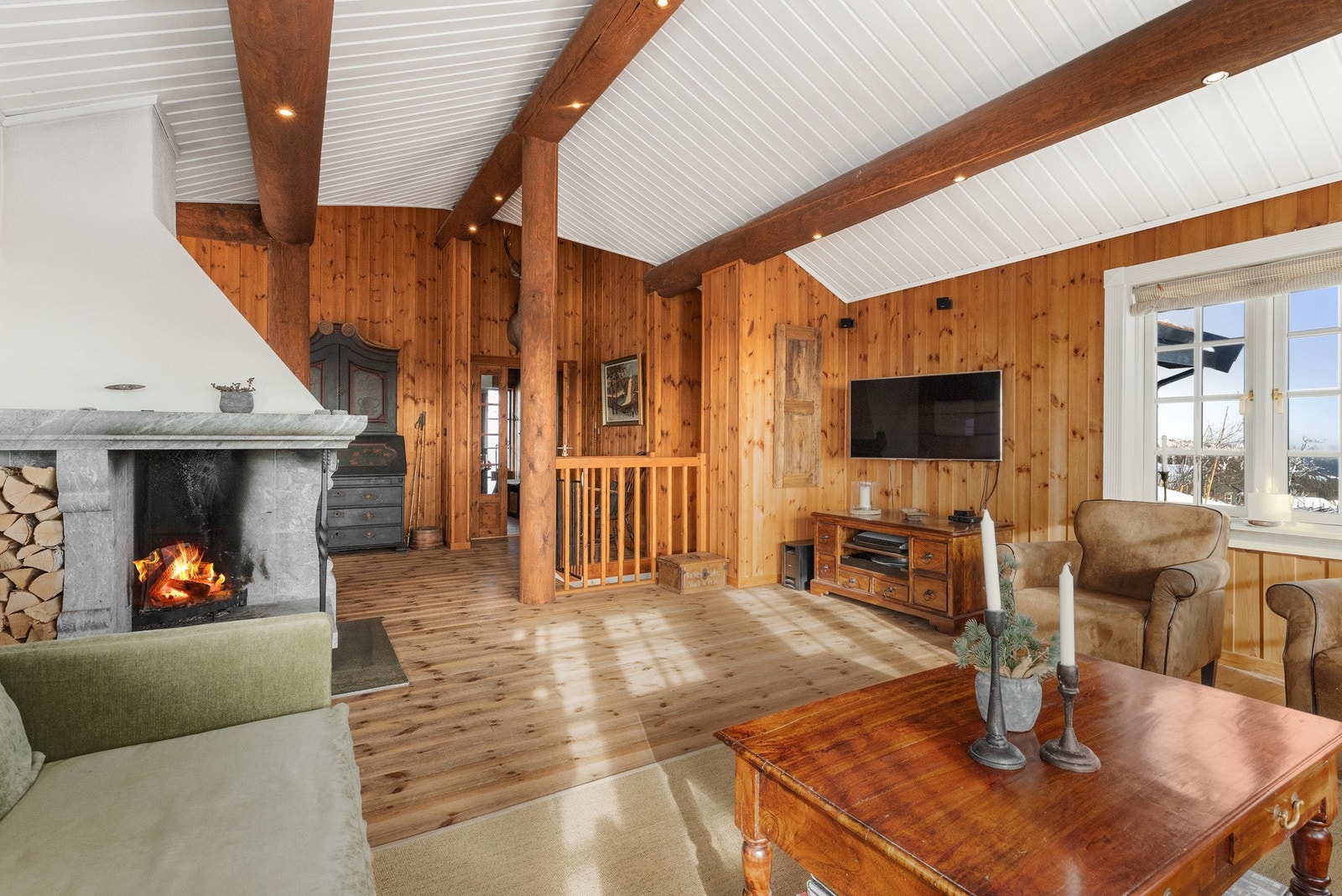 Stuen har god takhøyde med synlige tømmeråser, downlights i åsene Galleribilde