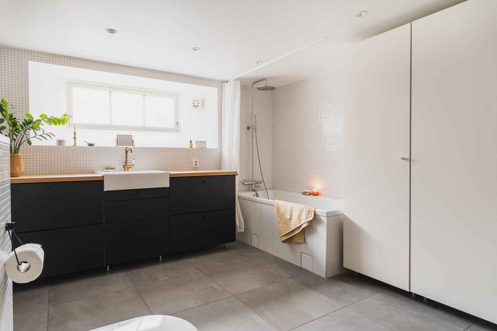 Baderommet er utstyrt med servant med innredning, badekar, veggfestet klosett og opplegg for vaskemaskin Galleribilde