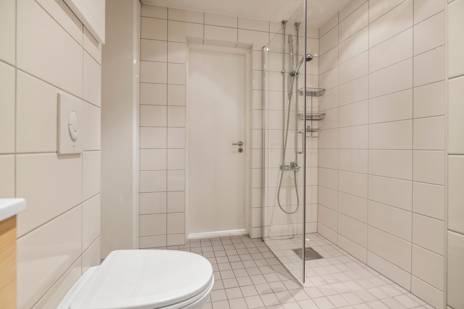 Badet har også et veggmontert toalett og dusj med glassdør Galleribilde