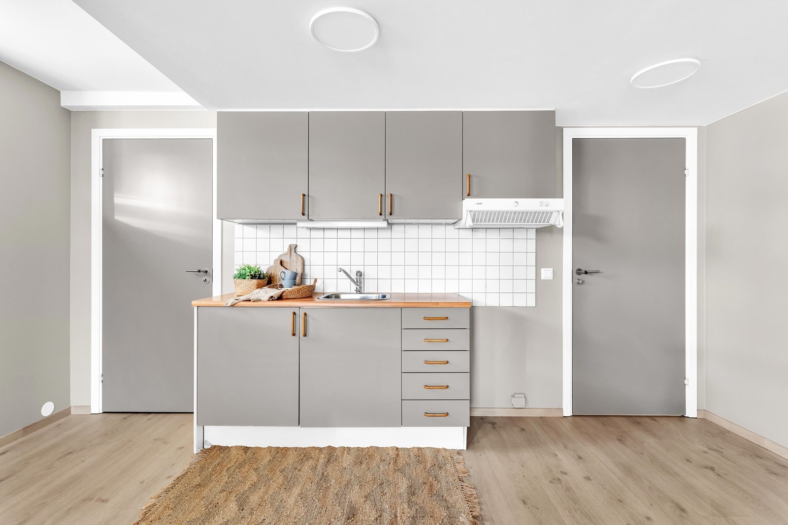 Kjøkkeninnredning med laminerte skrog, glatte fronter og laminert benkeplate med kjøkkenkum og plass til frittstående komfyr. Galleribilde