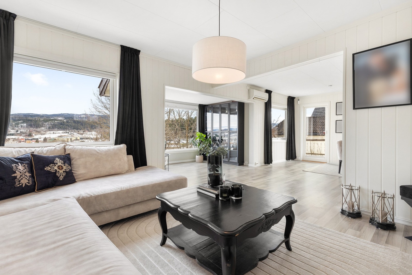 Boligen har en romslig stue med store vinduer som gir en luftig romfølelse Galleribilde