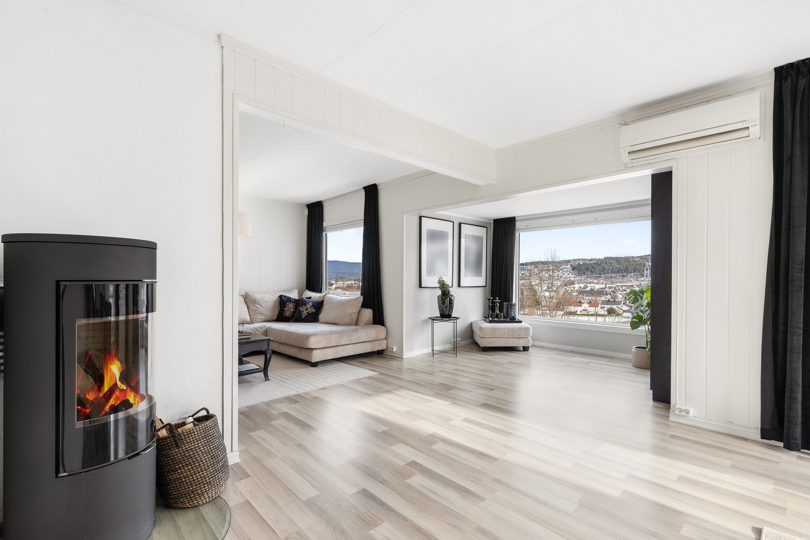 Moderne og lys stue i lyse farger. Det er montert peis og varmepumpe Galleribilde