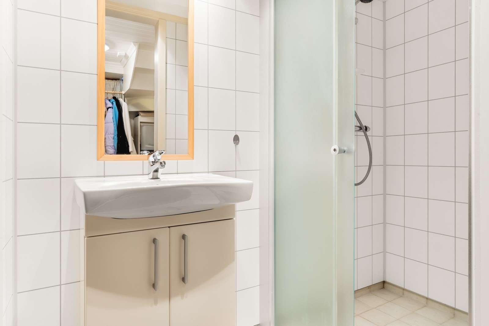 Dusjrommet har fliser på gulv med varme, samt innredet med servantinnredning, dusjhjørne og speil. Galleribilde