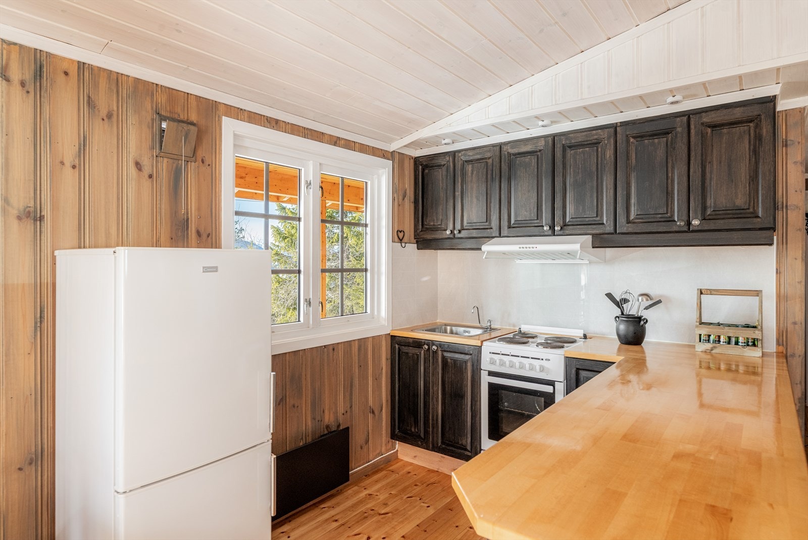 Spisestuen finner sin naturlige plass i fin tilknytning til kjøkkenet, hvor det er god skap- og benkeplass. Kjøkken har mørk innredning med profilerte fronter. Det er ventilasjon med avsug ut over stekesonen. Galleribilde