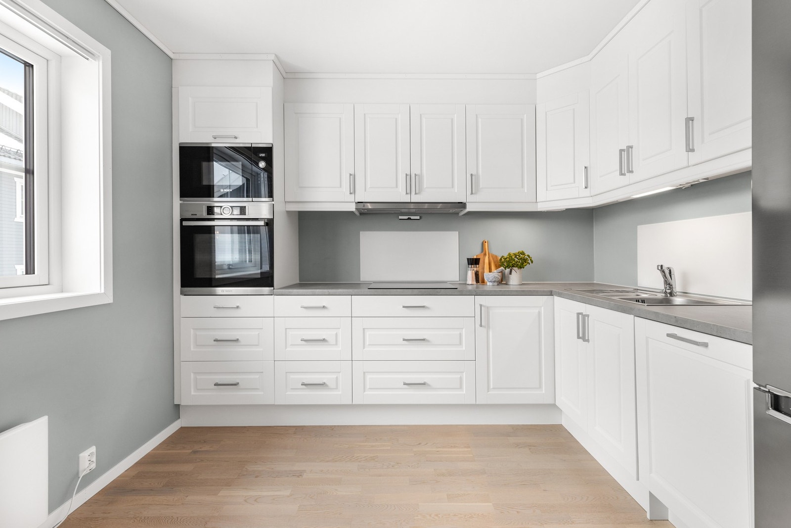 Innredningen har profilerte fronter og laminat benkeplate med nedfelt oppvaskkum og ett-greps kjøkkenarmatur Galleribilde